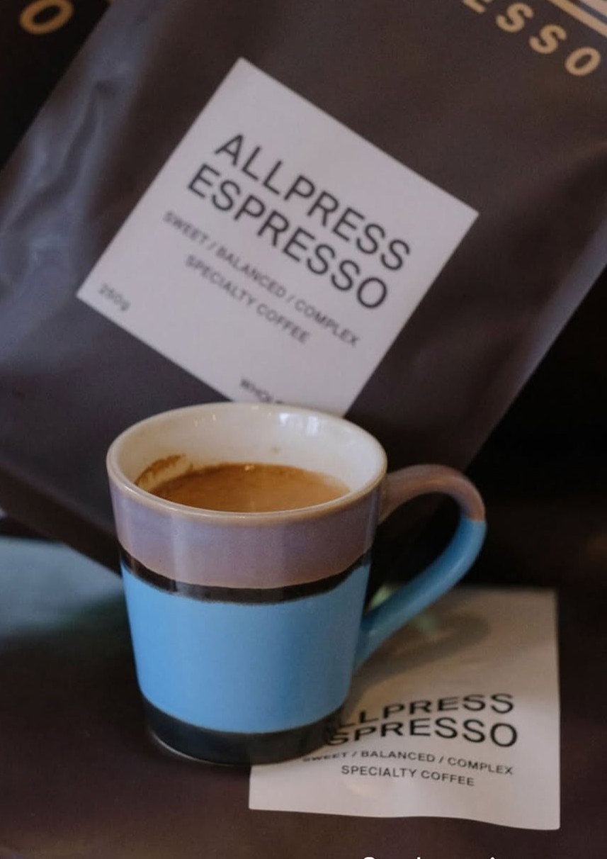 Coffee mug with coffee ontop of bags of coffee beans.