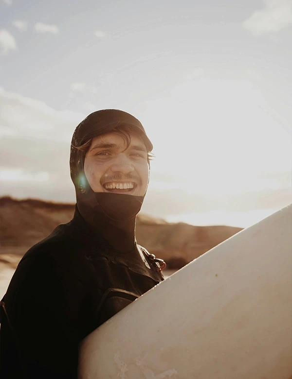 Homme en combinaison et avec une planche de surf