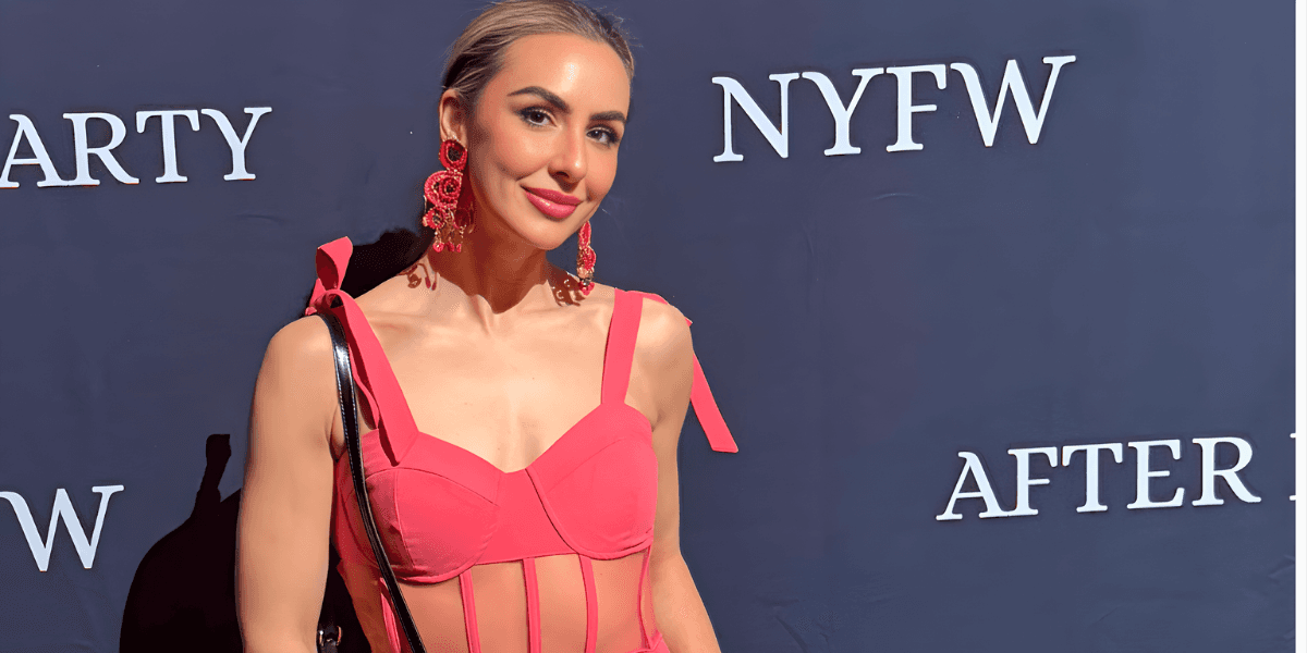 a woman at NYFW wearing a chic pink outfit, with bold earrings, embodying a refined beauty look.