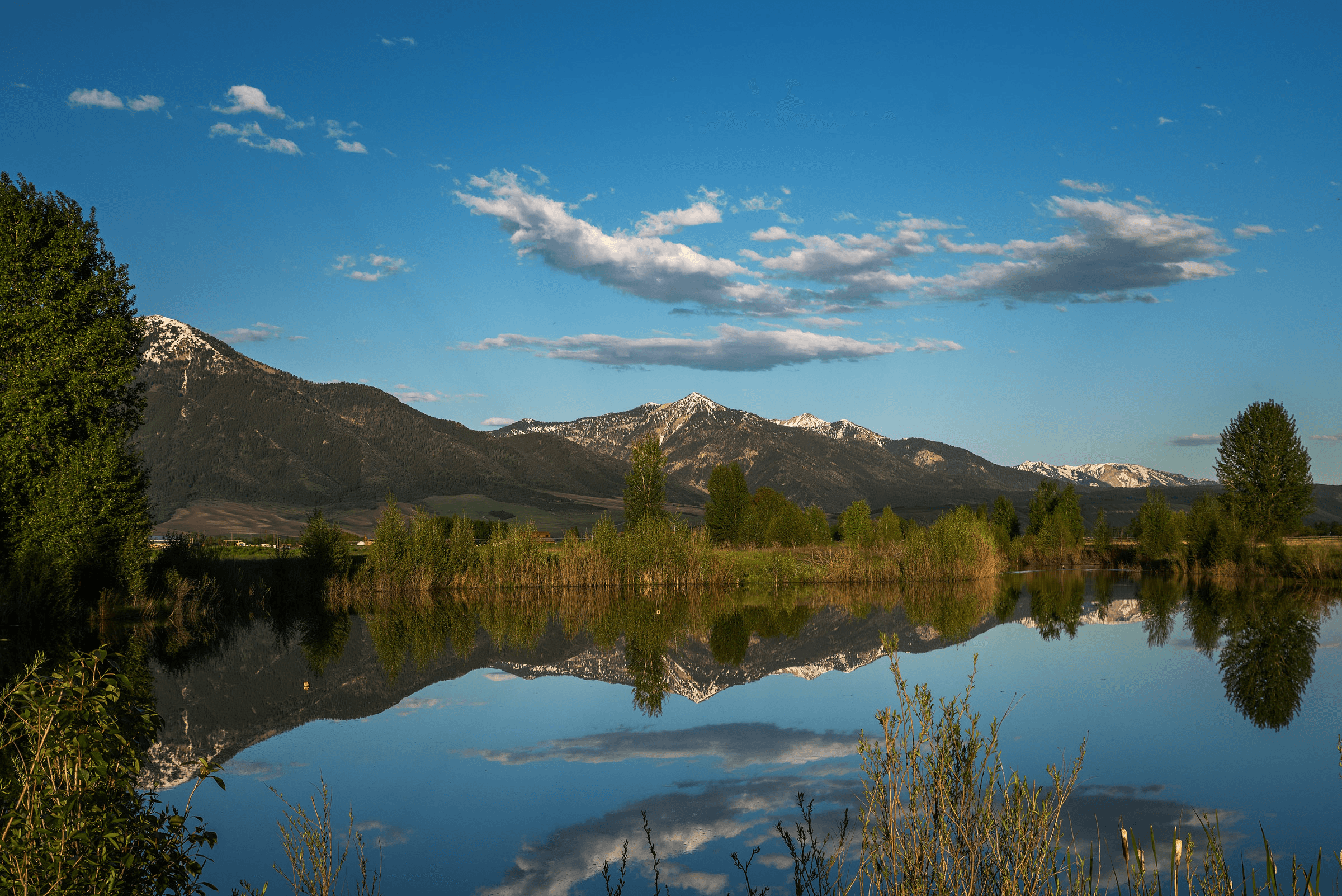 Mountains reflected in calm lake under blue sky.