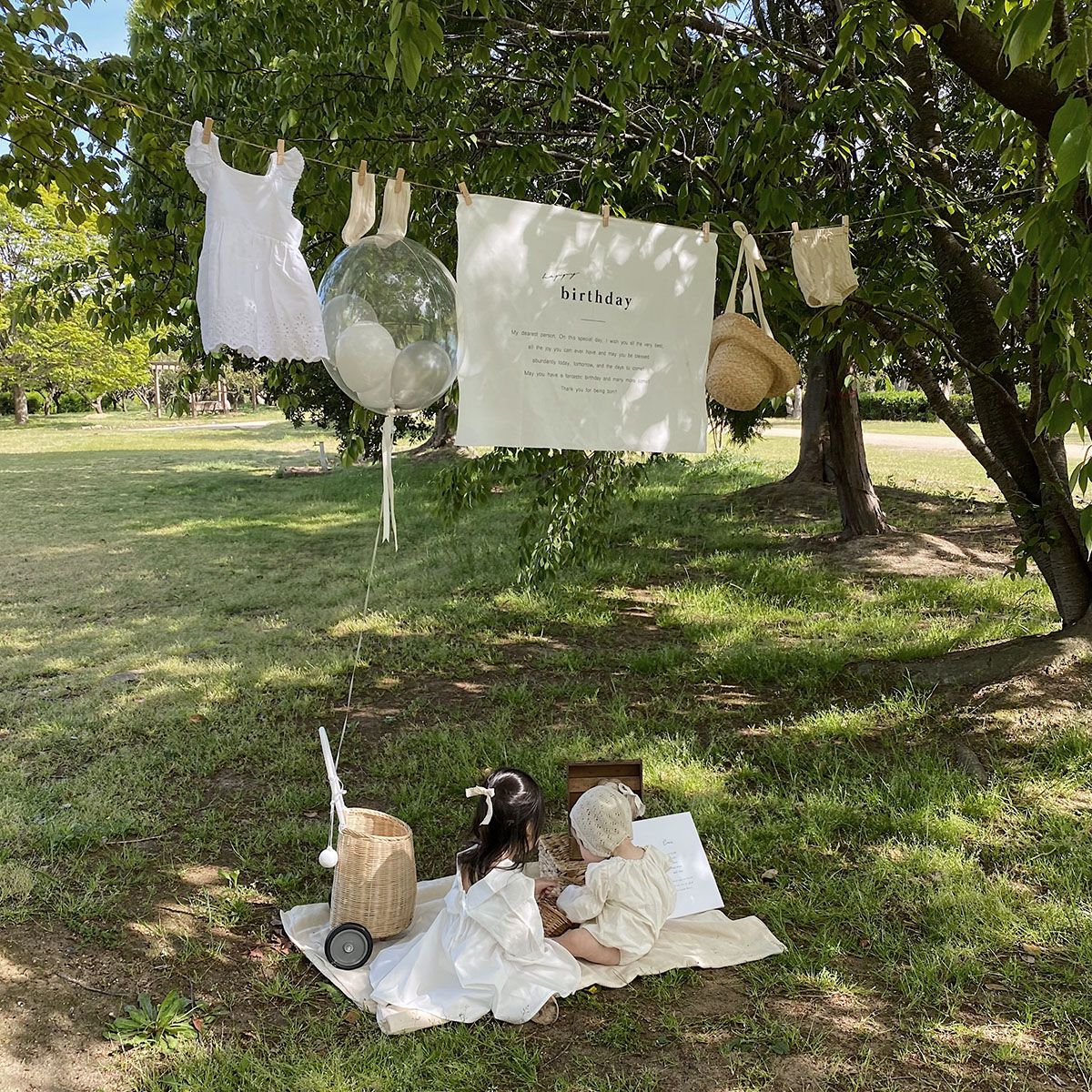 Outdoor birthday shoot of a child in a garden with clothesline and picnic styling