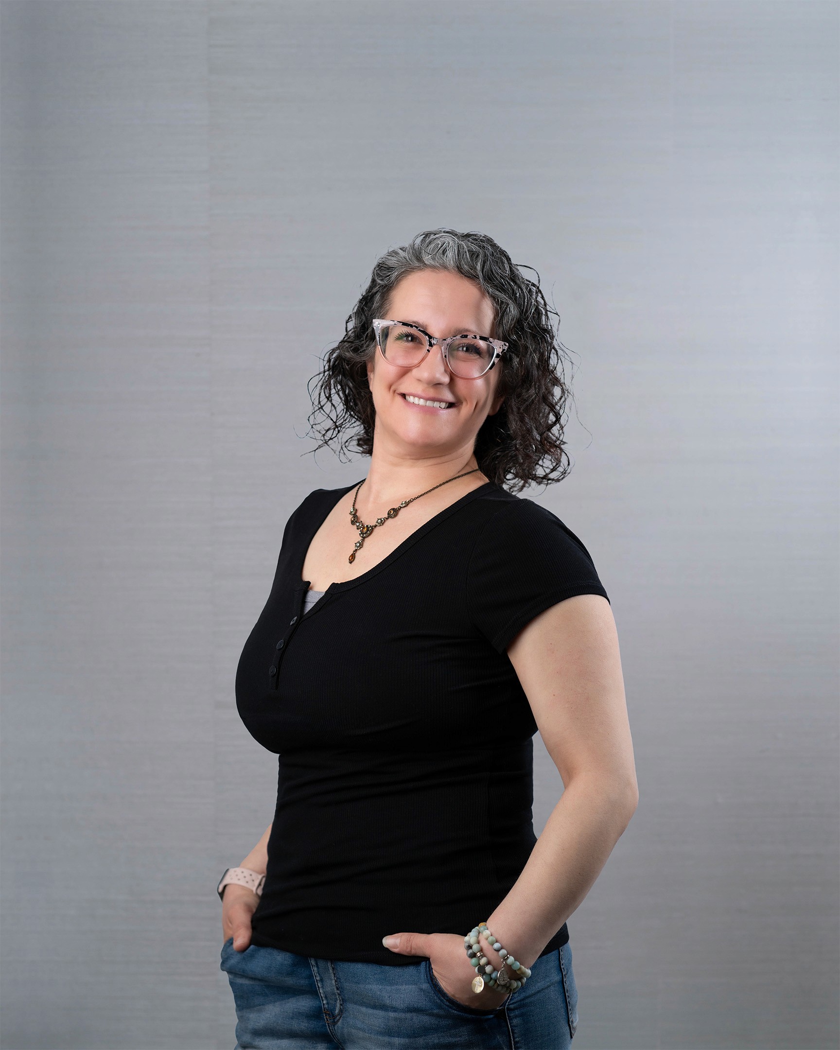 Woman with grey curly hair, smiling brightly.