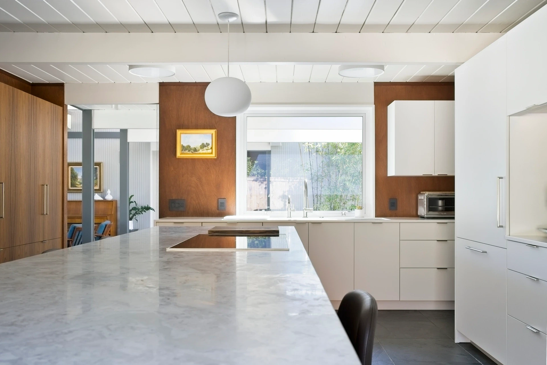 Close-up of the kitchen island surface, looking towards the sink wall and Fleetwood awning window, blending luxury with simplicity in the Eichler kitchen. Photo by Todd Huge.