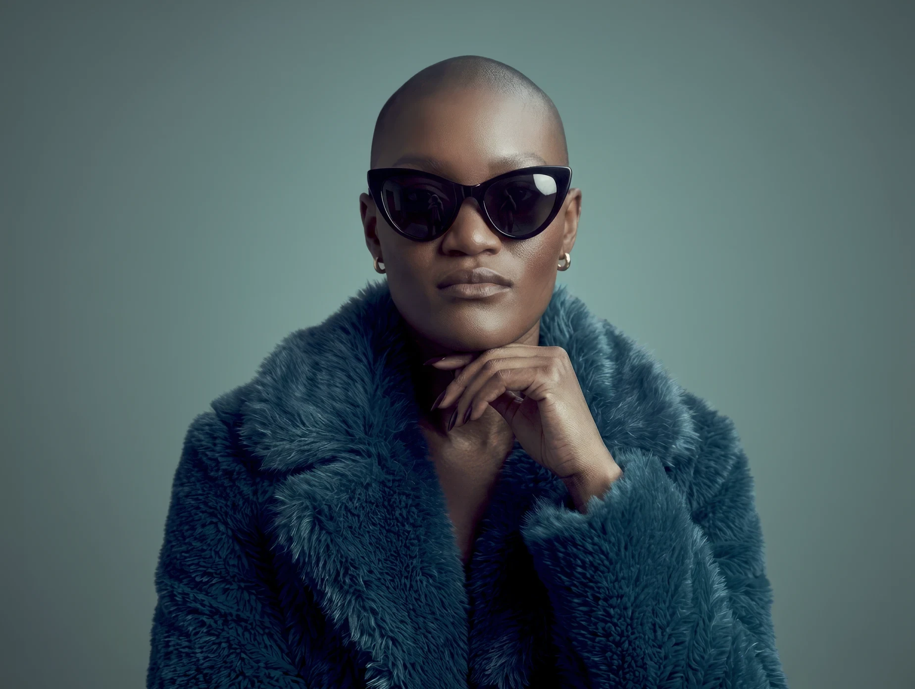 Studio portrait of a model wearing sunglasses and a textured coat from Holloway fashion label.