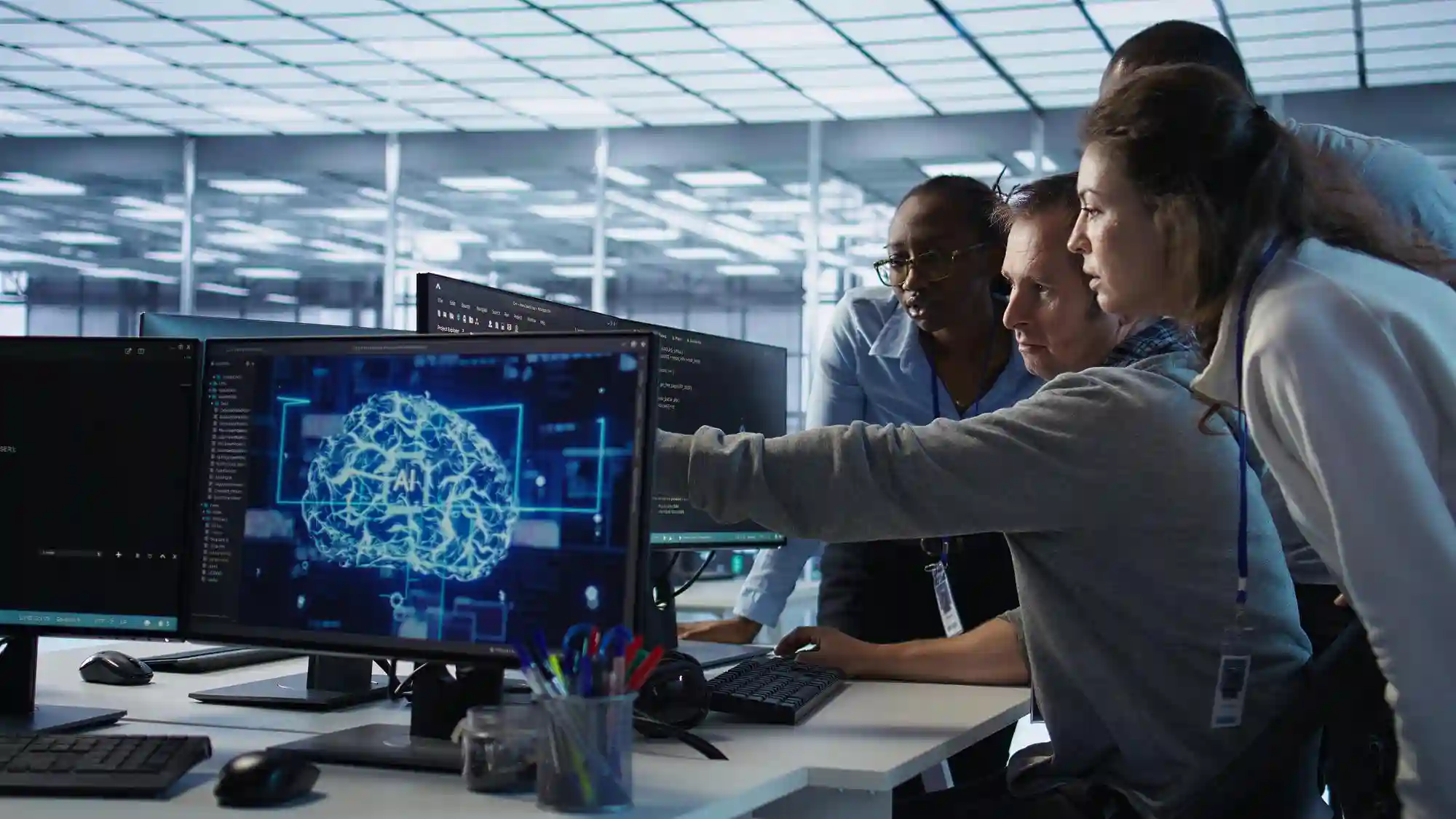 Diverse group of young professionals collaborating on a laptop in a modern, casual office lounge setting.