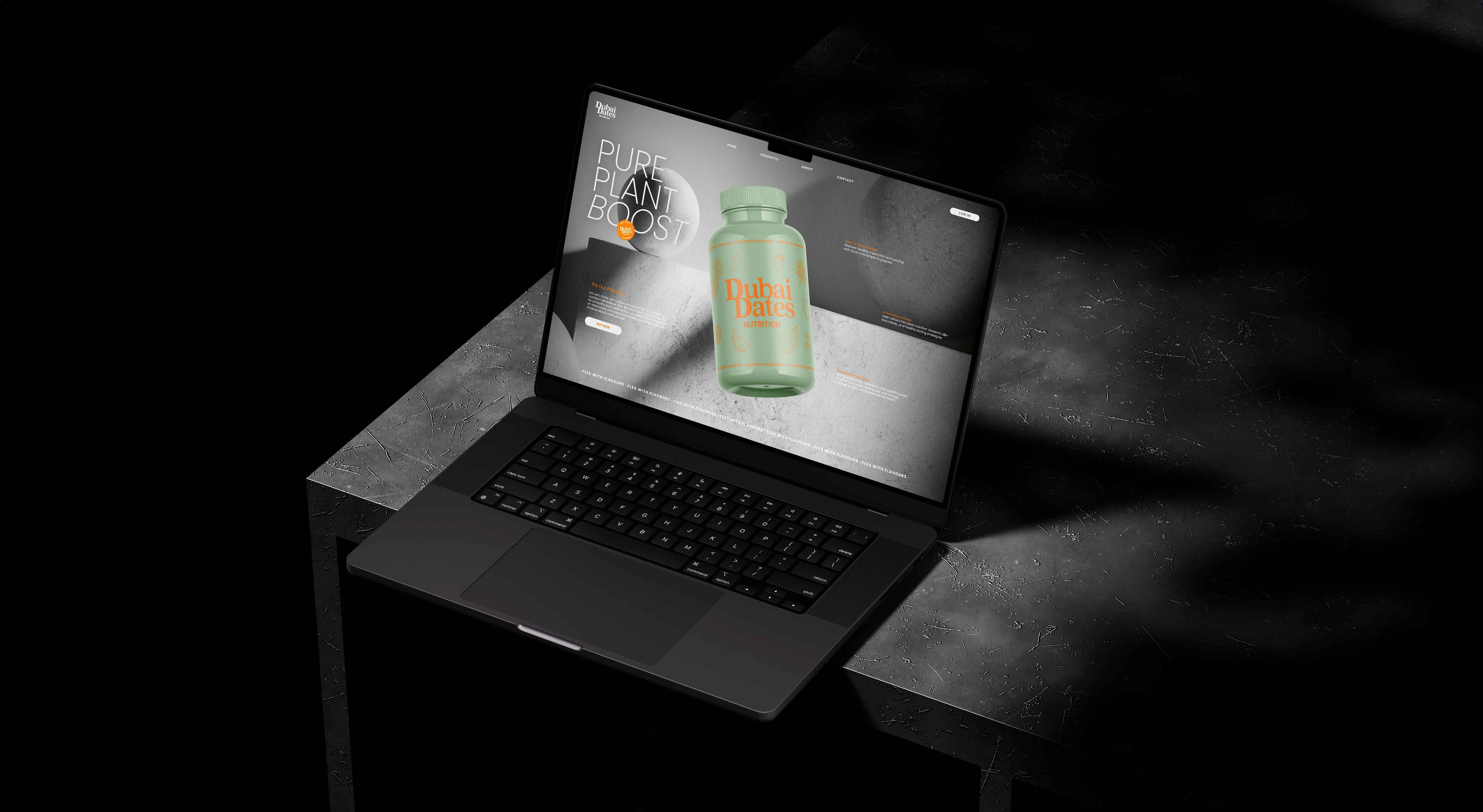 A laptop displaying the dubai dates website on a dark, textured marble table. The screen shows a grey background with a green jar and the Dubai Dates Nutrition logo in the center.