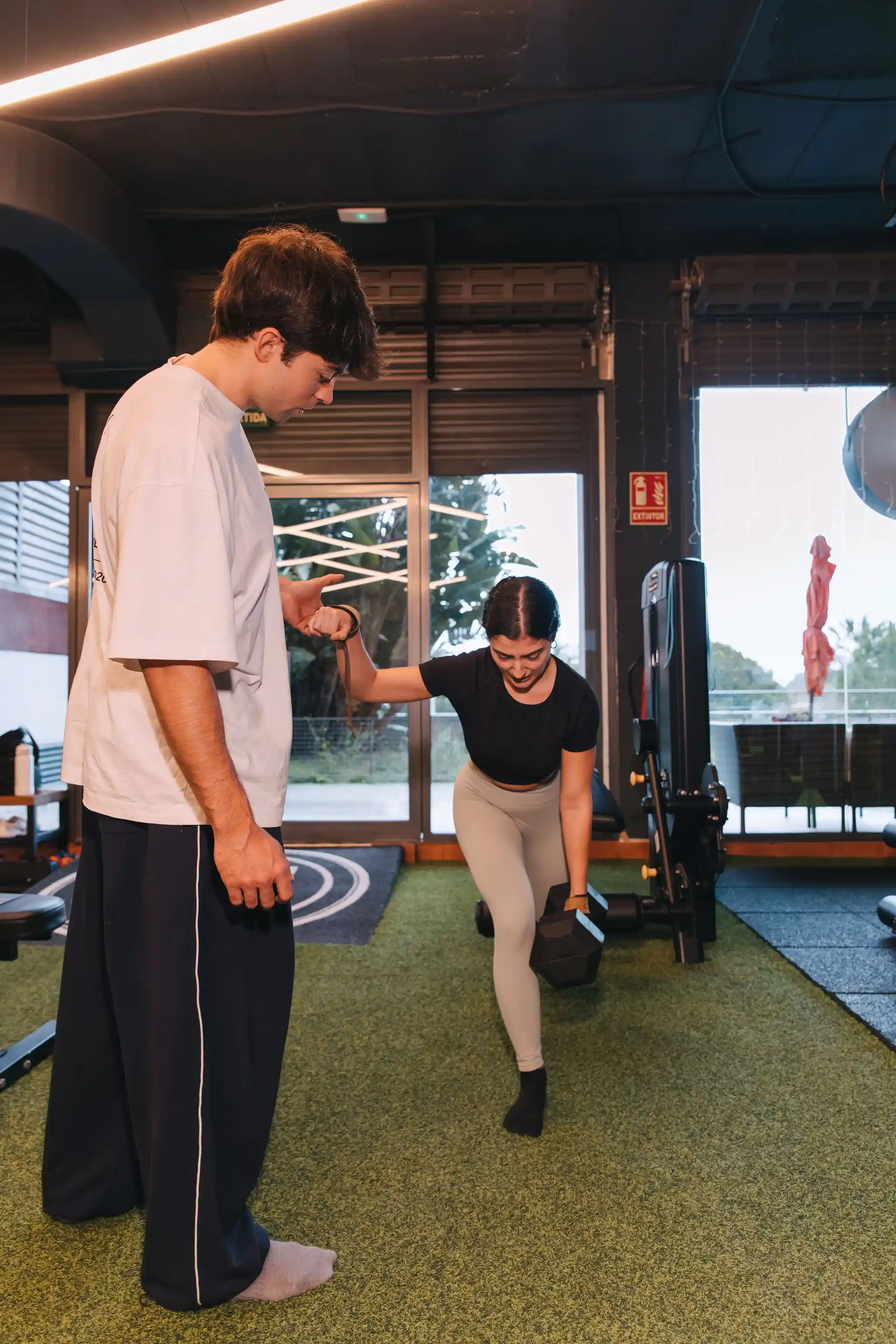 Entrenador corrigiendo técnica de sentadilla a clienta en La Base Strength, Sitges