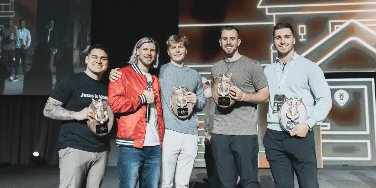 Five door-to-door sales representatives pose on stage holding award plaques at a D2D Games event.