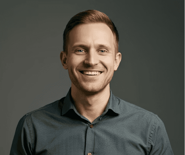 A man wearing a blue shirt smiles warmly at the camera.