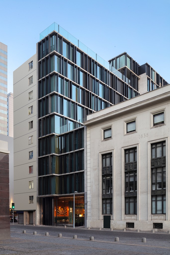 Modern glass building adjacent to a classic stone structure, showcasing contrasting architectural styles.
