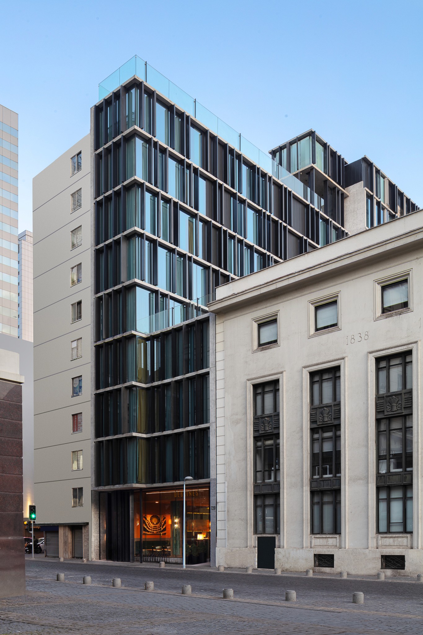 Modern glass building adjacent to a classic stone structure, showcasing contrasting architectural styles.