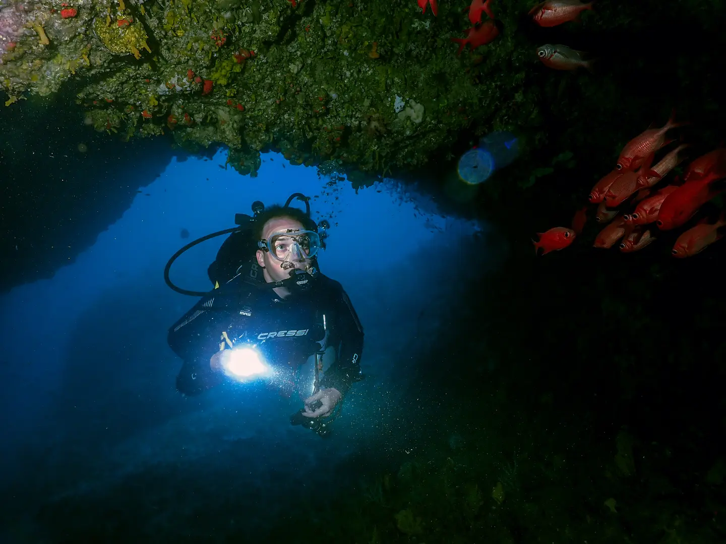 A scuba diver doing a cave dive with a torch in his hand