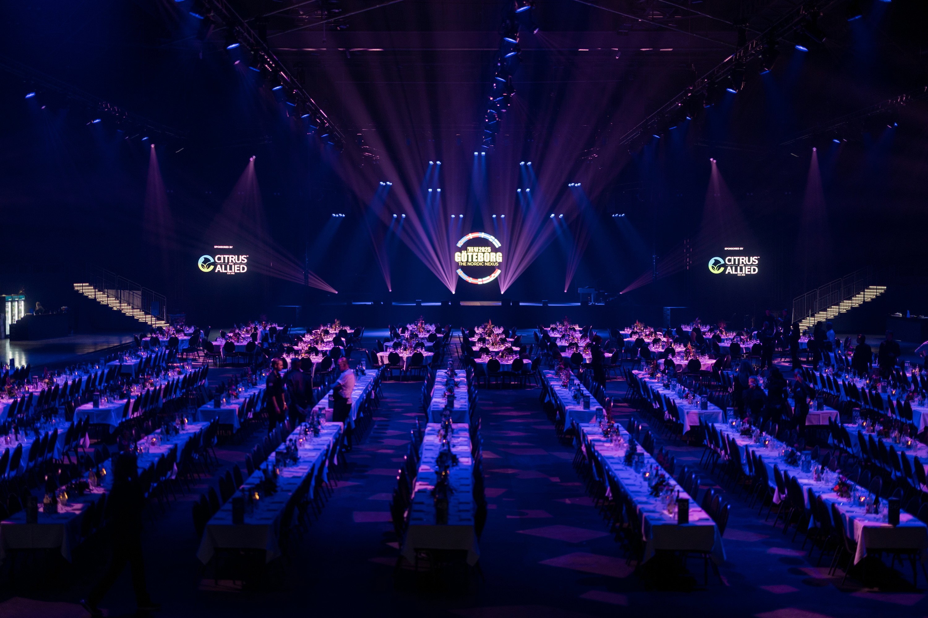 large event space filled with chairs and tables underneath purple strobe lights