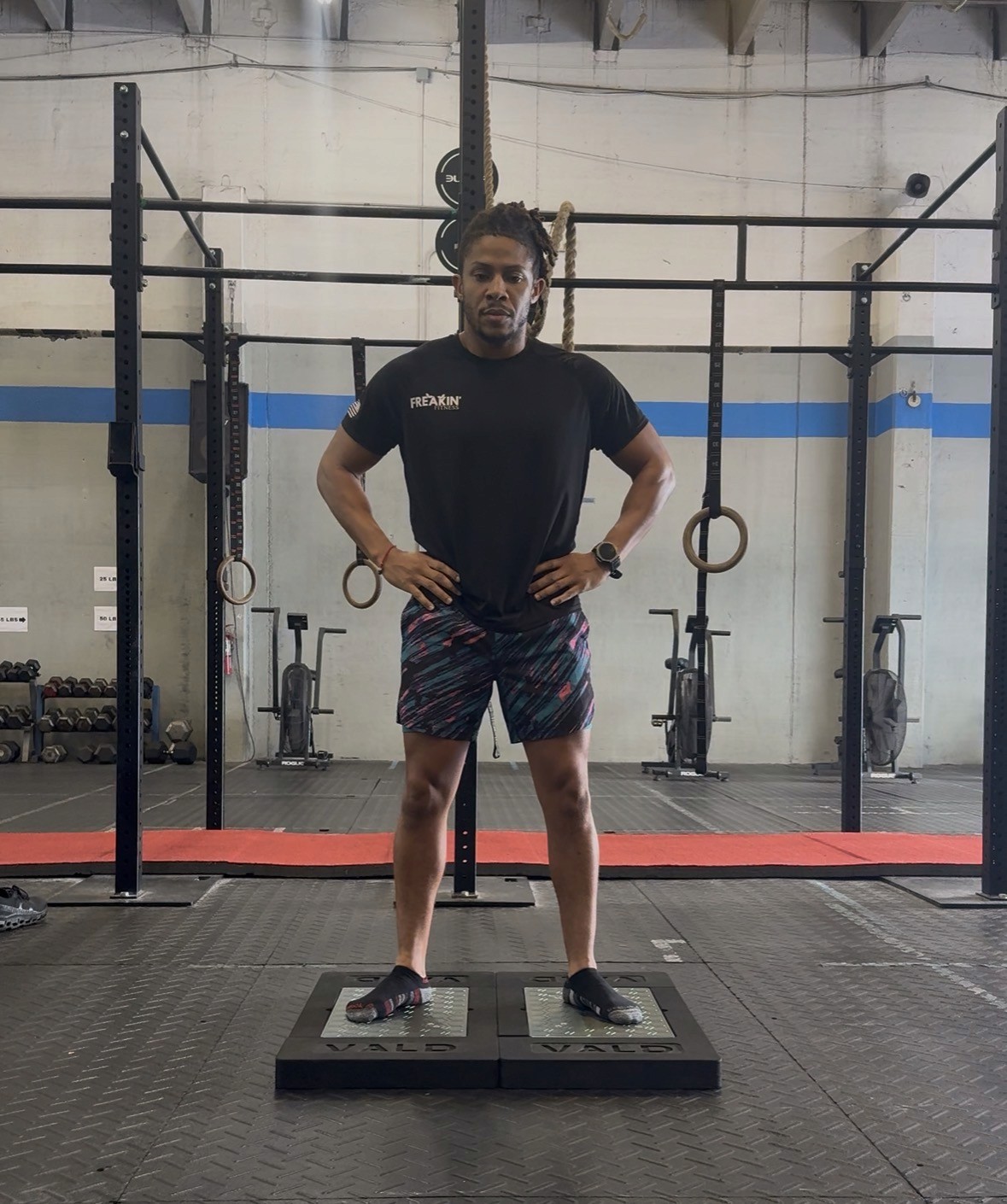 Focused female athlete performing a hip mobility stretch on the gym floor beside a medicine ball—enhancing flexibility, joint health, and rehab-focused recovery.