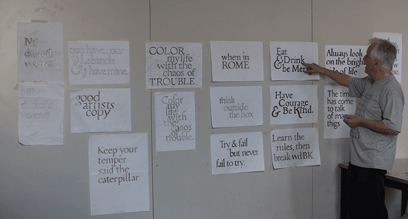 man pointing at paper with type on wall