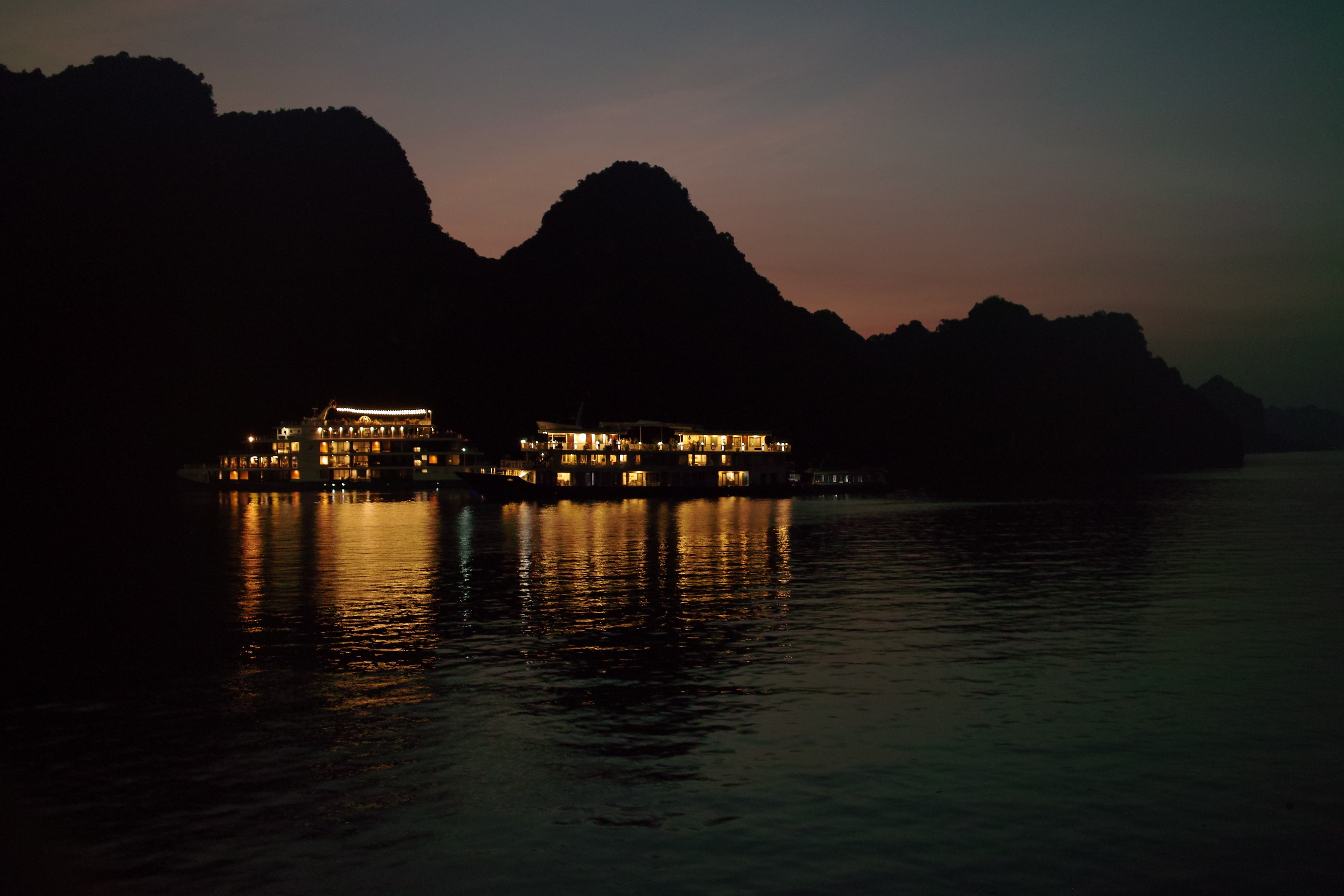 Photo de nuit de bateaux de tourisme à l'arrêt dans la montagneuse baie d'Ha Long