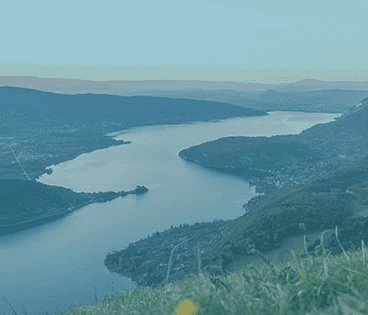 a body of water with boats in it and mountains in the back
