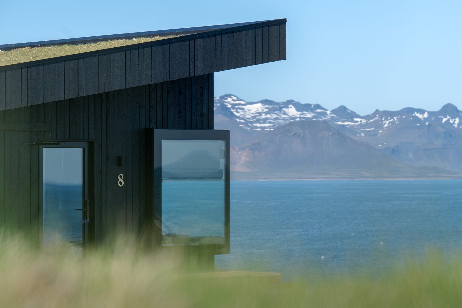Peninsula Suites Building in Black with number 8 on it and mountains and sea in the background