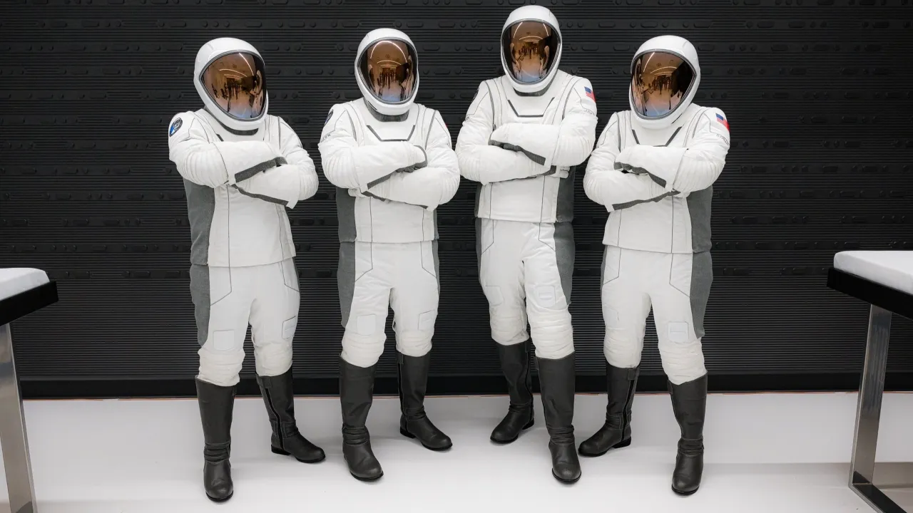 Four astronauts in sleek white space suits and visors stand confidently with arms crossed in a modern, minimalistic setting, highlighting the theme of space exploration.
