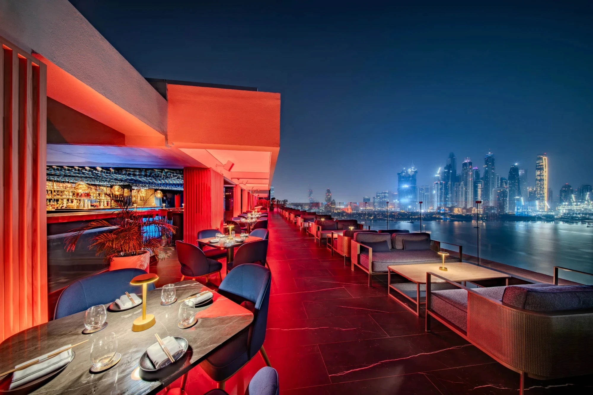 Marina Terrace at The Penthouse Dubai with lounge sofas, dining tables and the Dubai Marina skyline at night