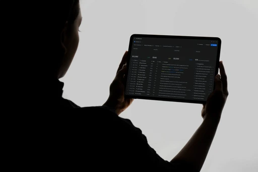 A person in silhouette holds a tablet displaying a detailed digital product interface for pre-bill review, showcasing.