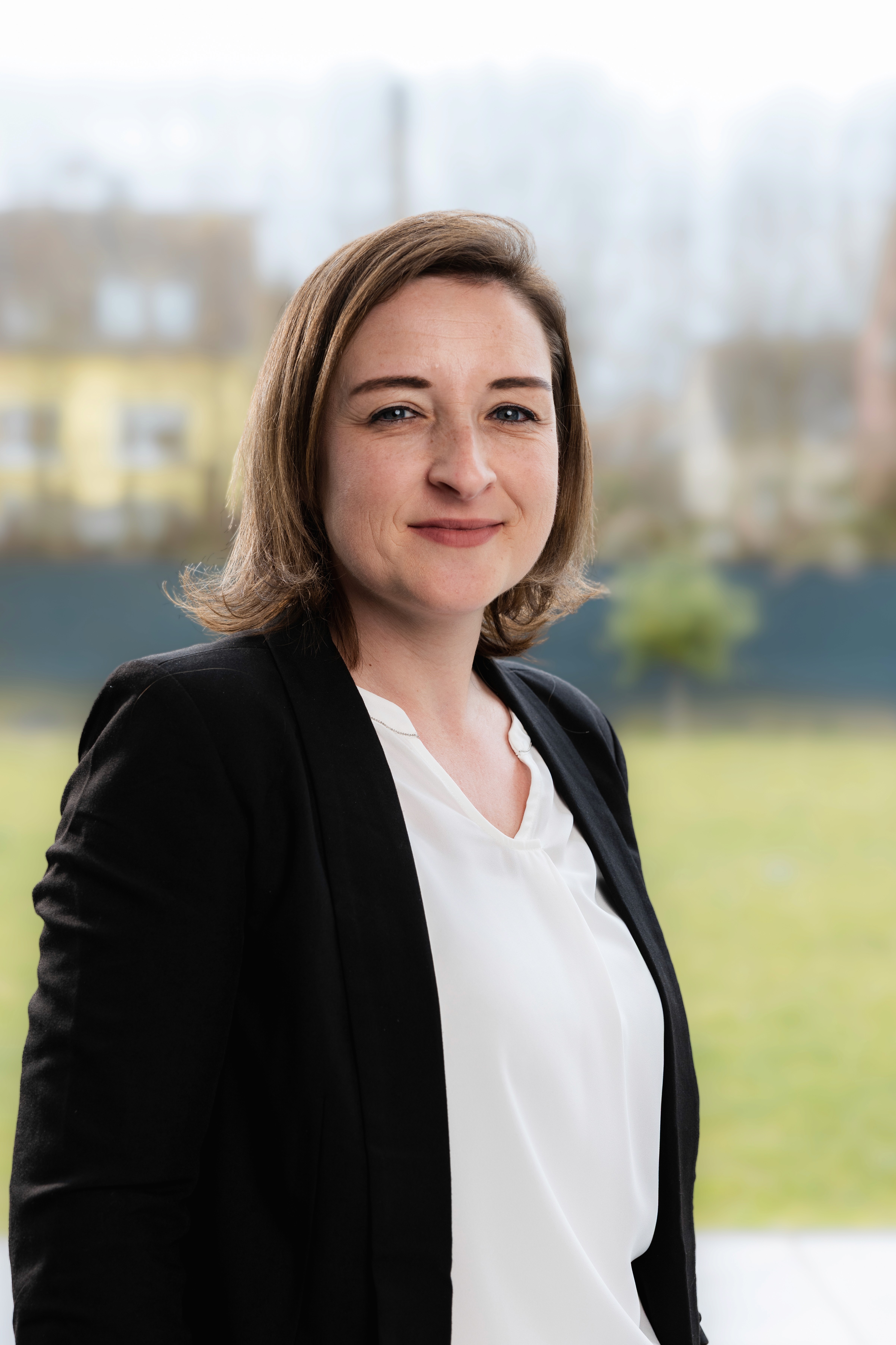Smiling man in a blue beanie and black hoodie against a brick wall, exuding a joyful and relaxed vibe.