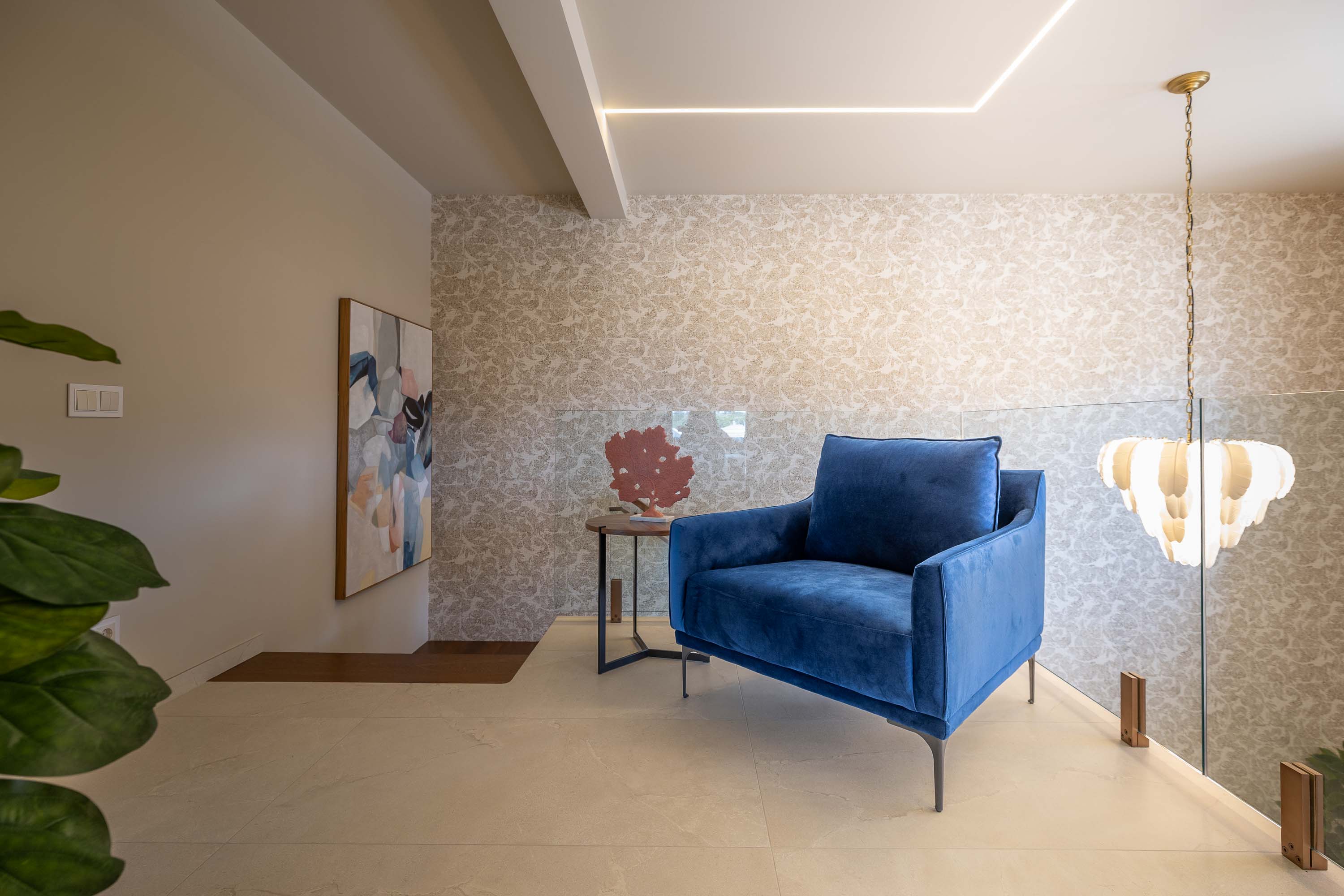 Blue velvet armchair and a side table in a pale hallway