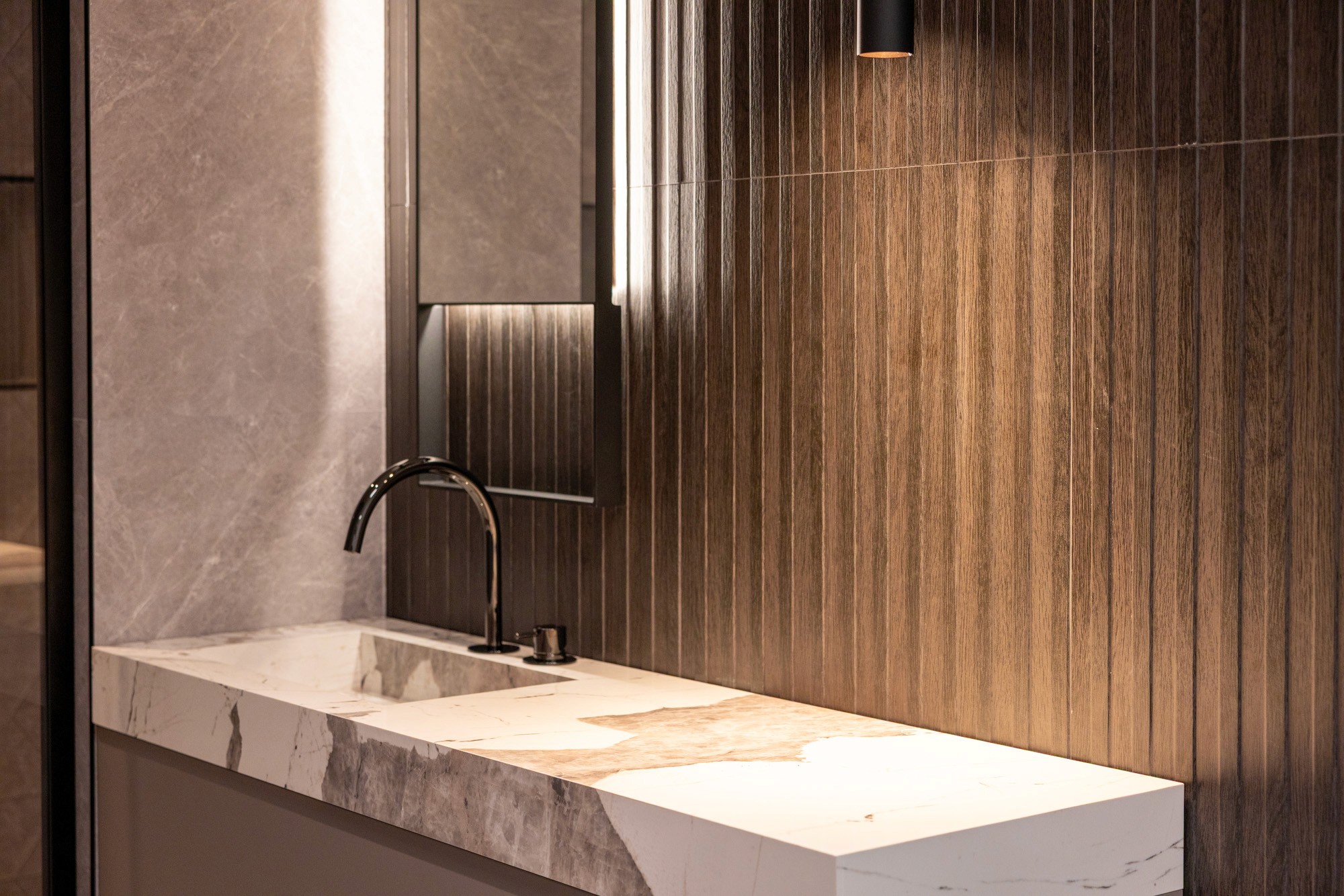 Man with a beard in a dark button-up shirt, smiling while writing in a notebook.