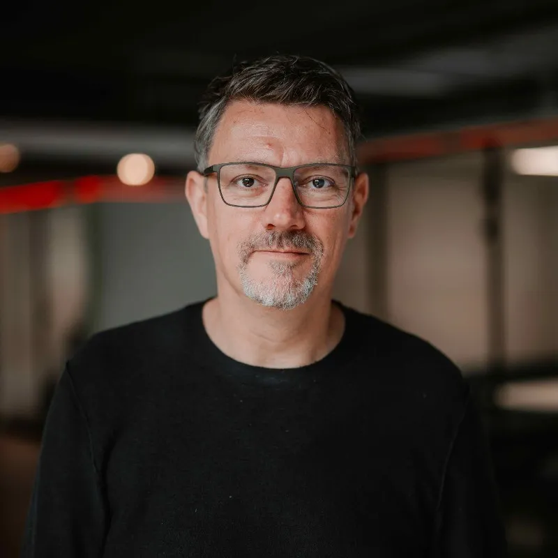 Ein Portraitfoto von Adreas Kämmer, der in einem Bürogebäude steht.