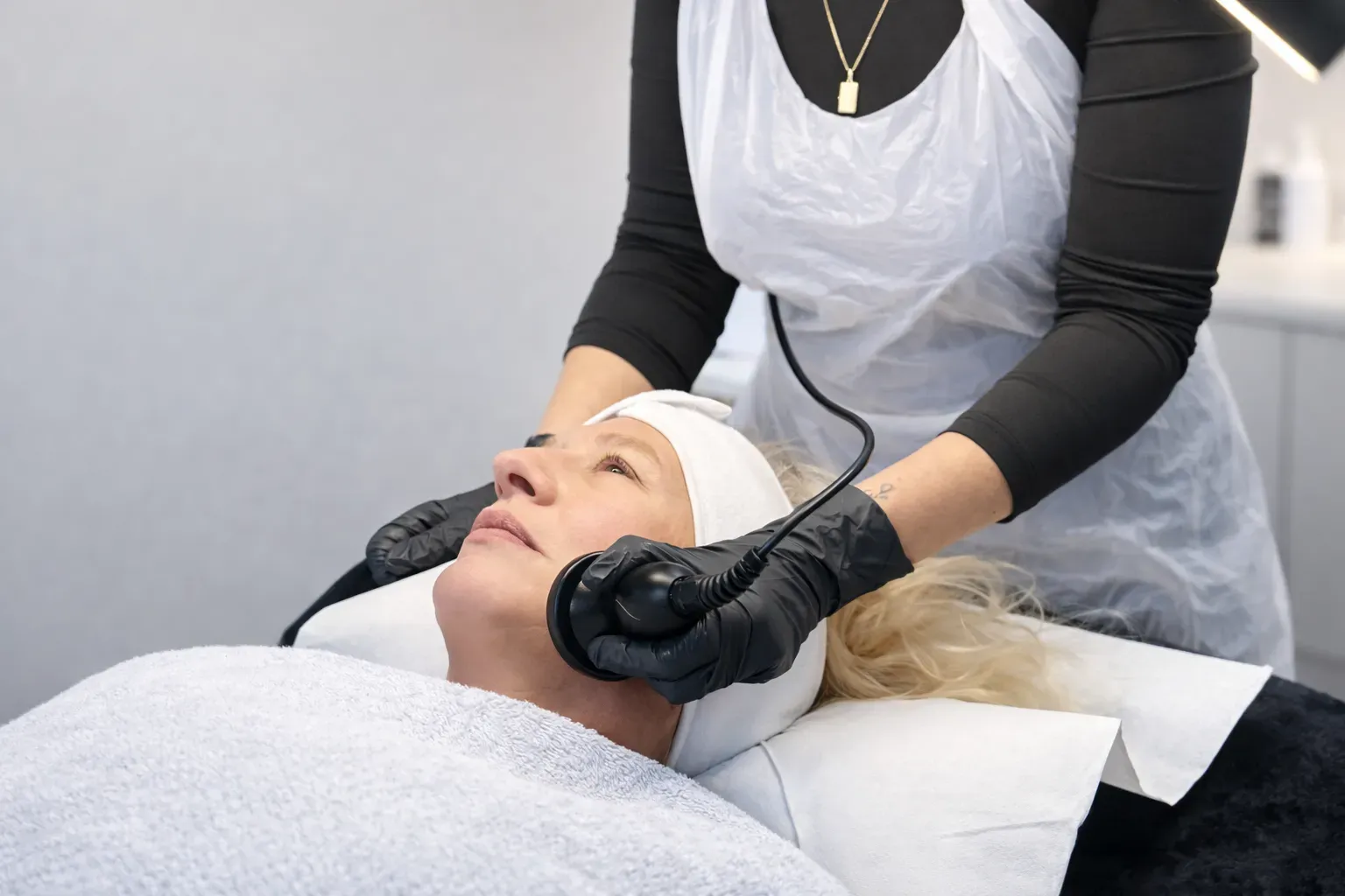 Client receiving a radiofrequency facial treatment to improve skin firmness in a professional clinic setting.