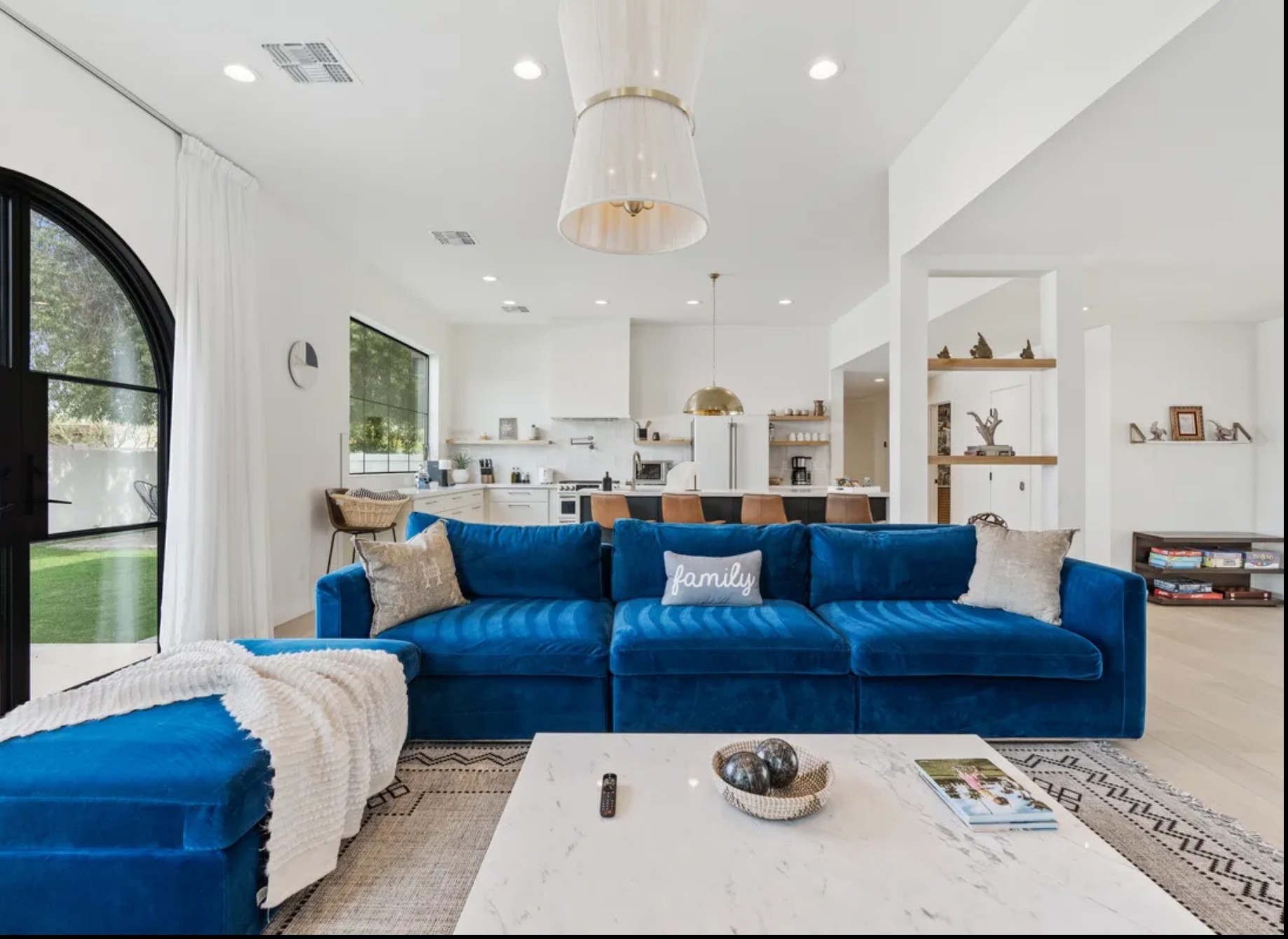 Close-up of a warm living space featuring a stone fireplace, a burnt orange accent chair with a striped pillow, a woven rug, and built-in shelves with decorative items