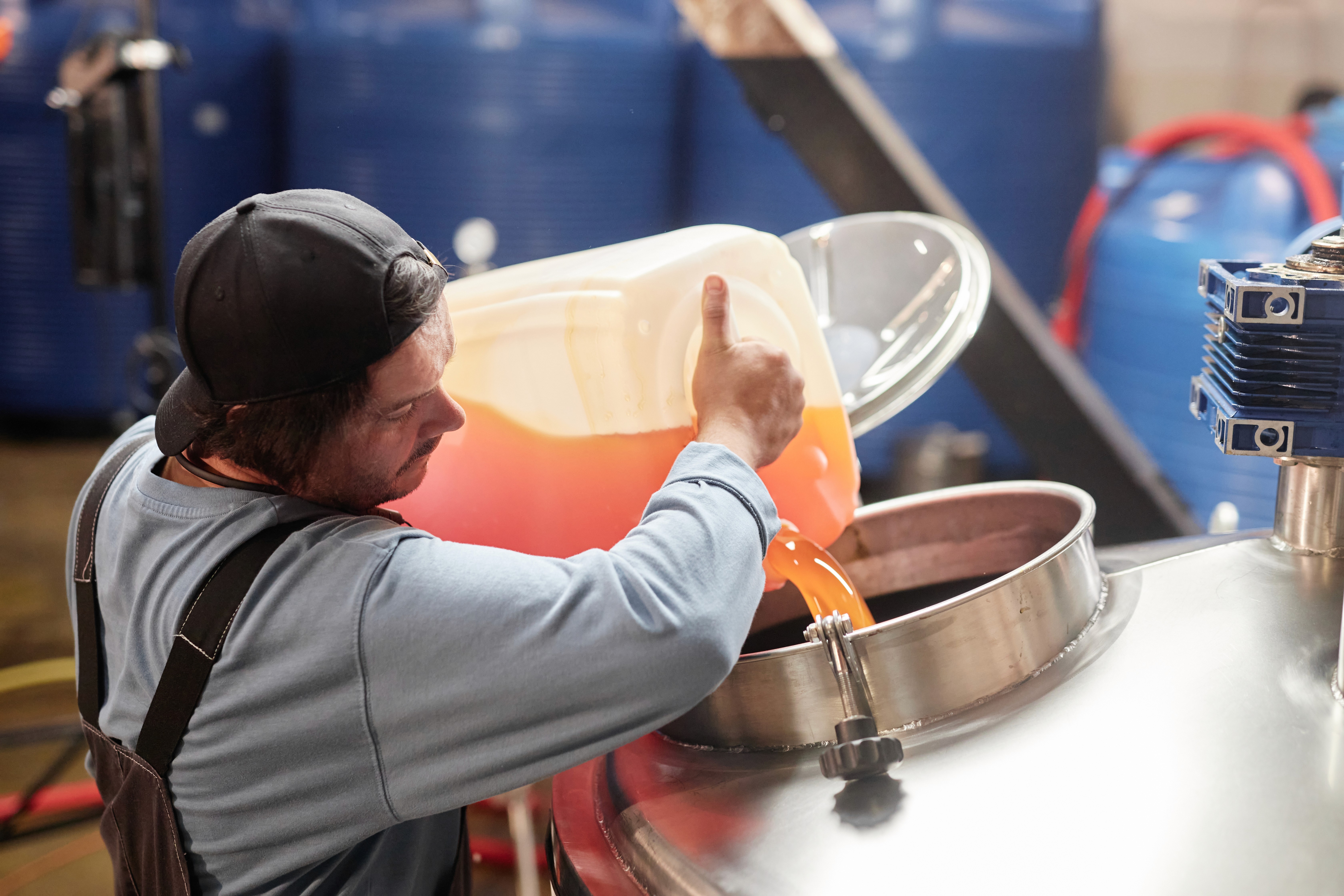 Male Factory Worker Pouring Liquid into Tank