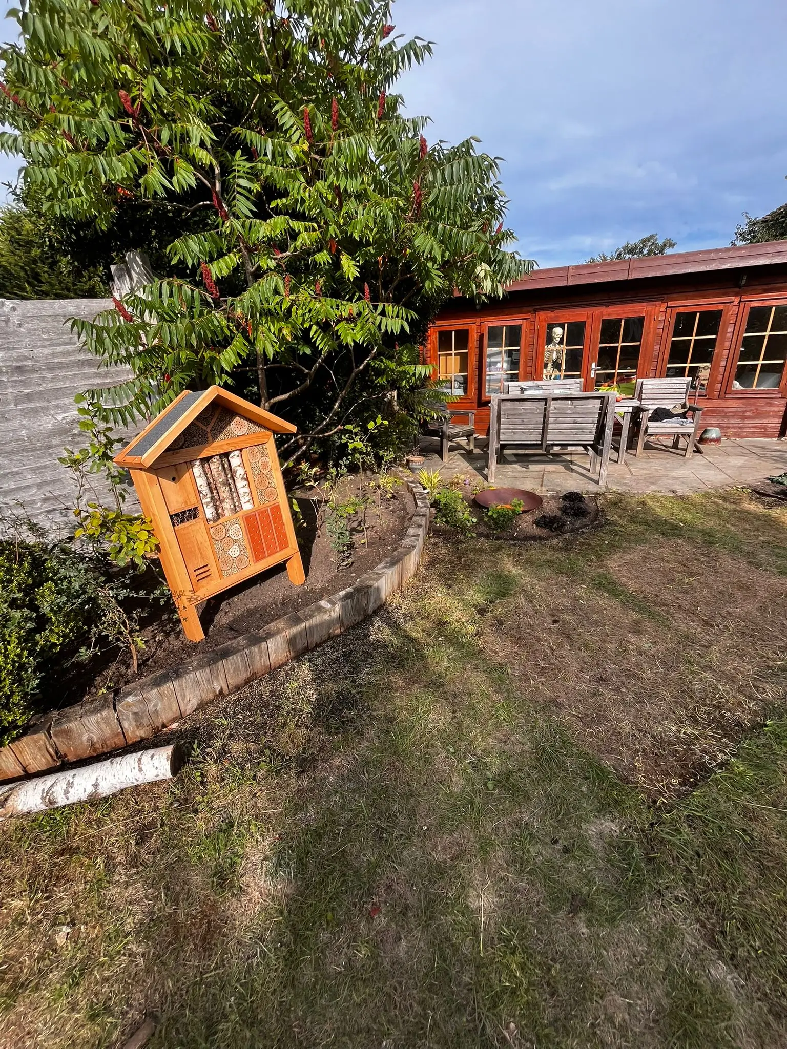 A small wooden structure is visible near a well-kept yard, with a house in the background and trees overhead.