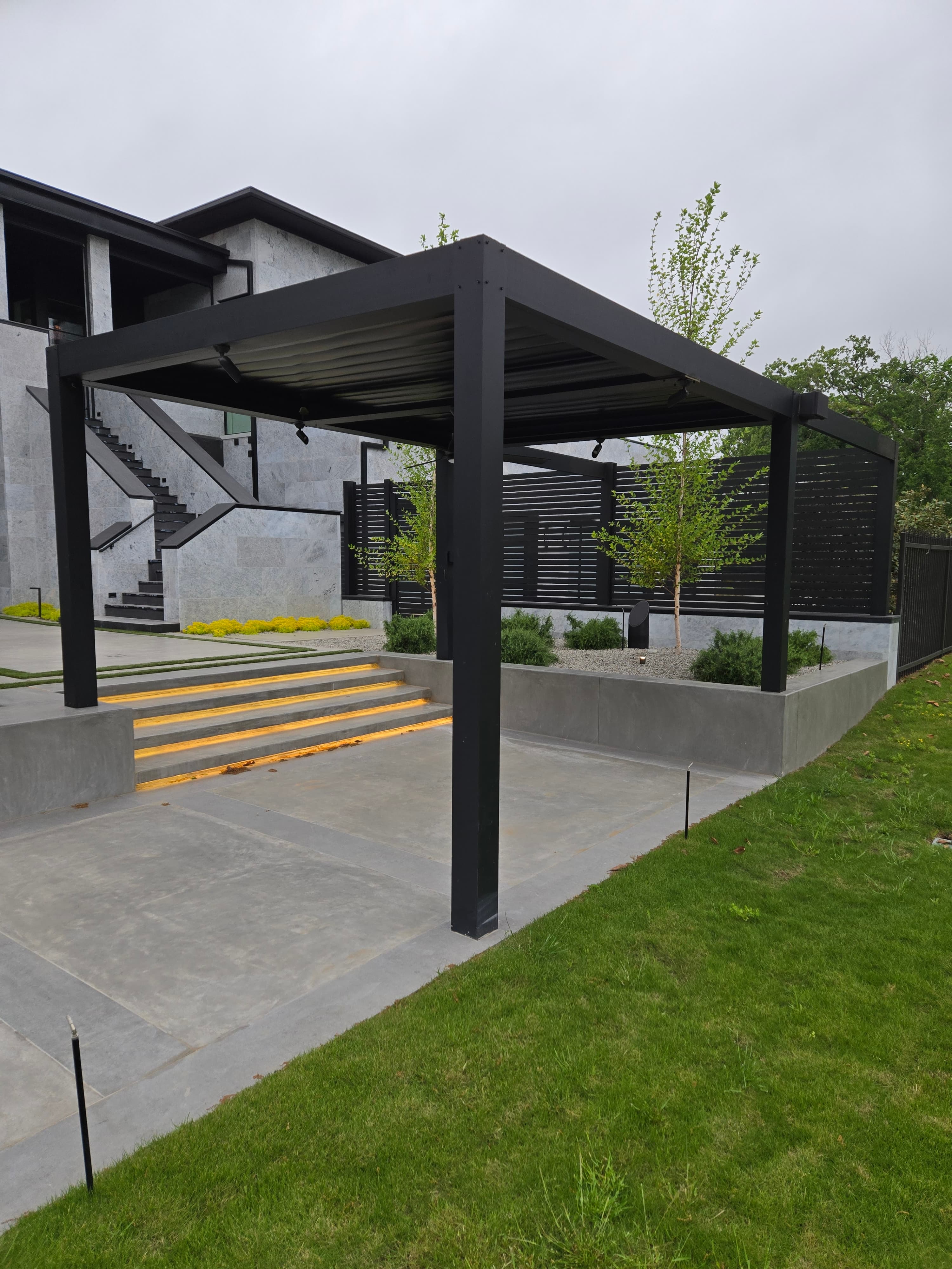 Detail of the custom steel pergola with linear shade members and adjacent cantilevered concrete steps
