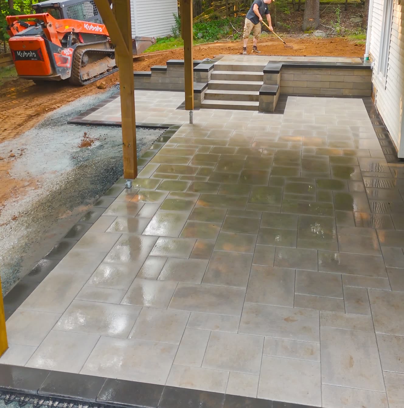 Paver patio under construction with a compact track loader on site