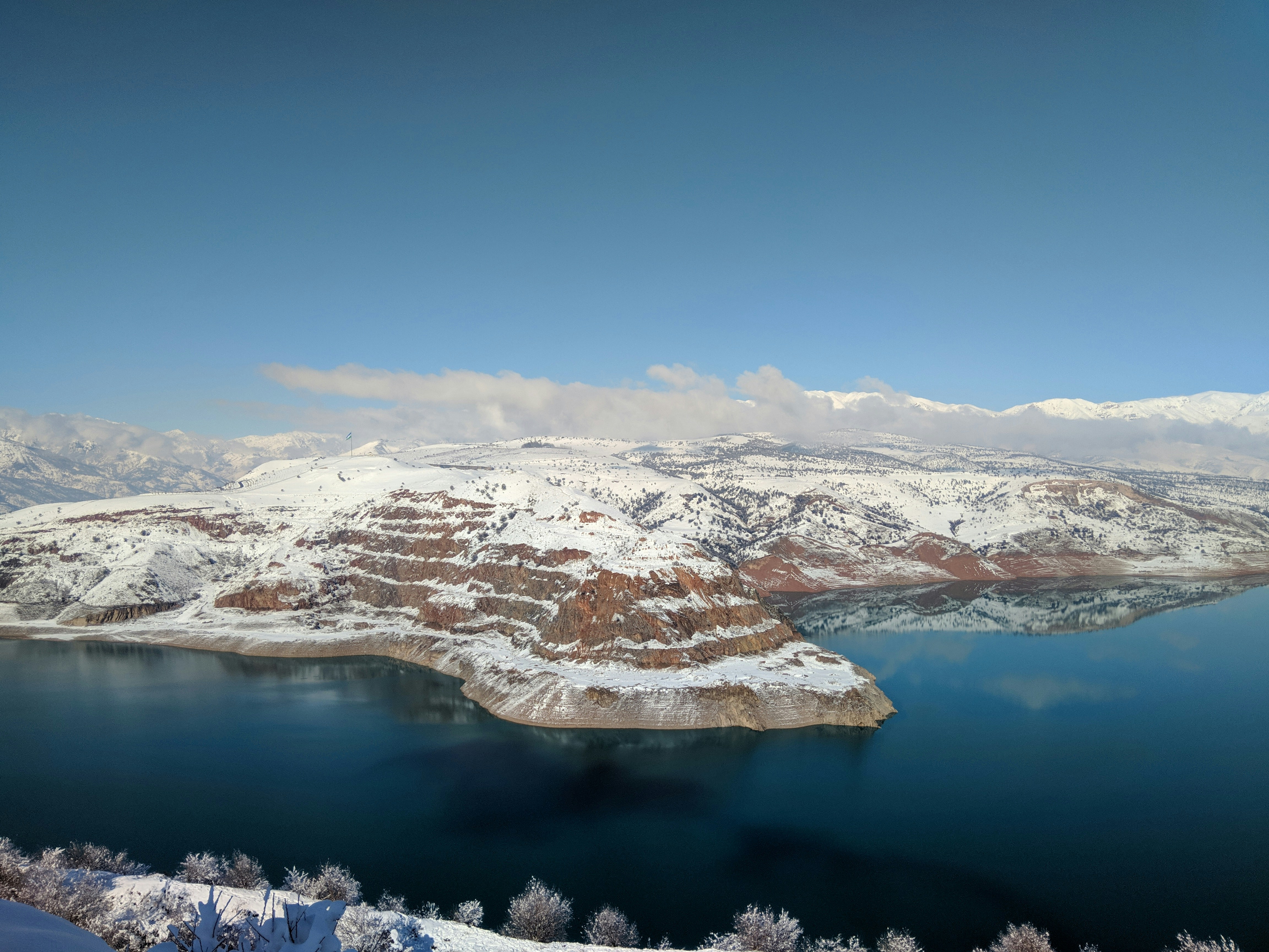 snow covered mountains near body of water during daytime