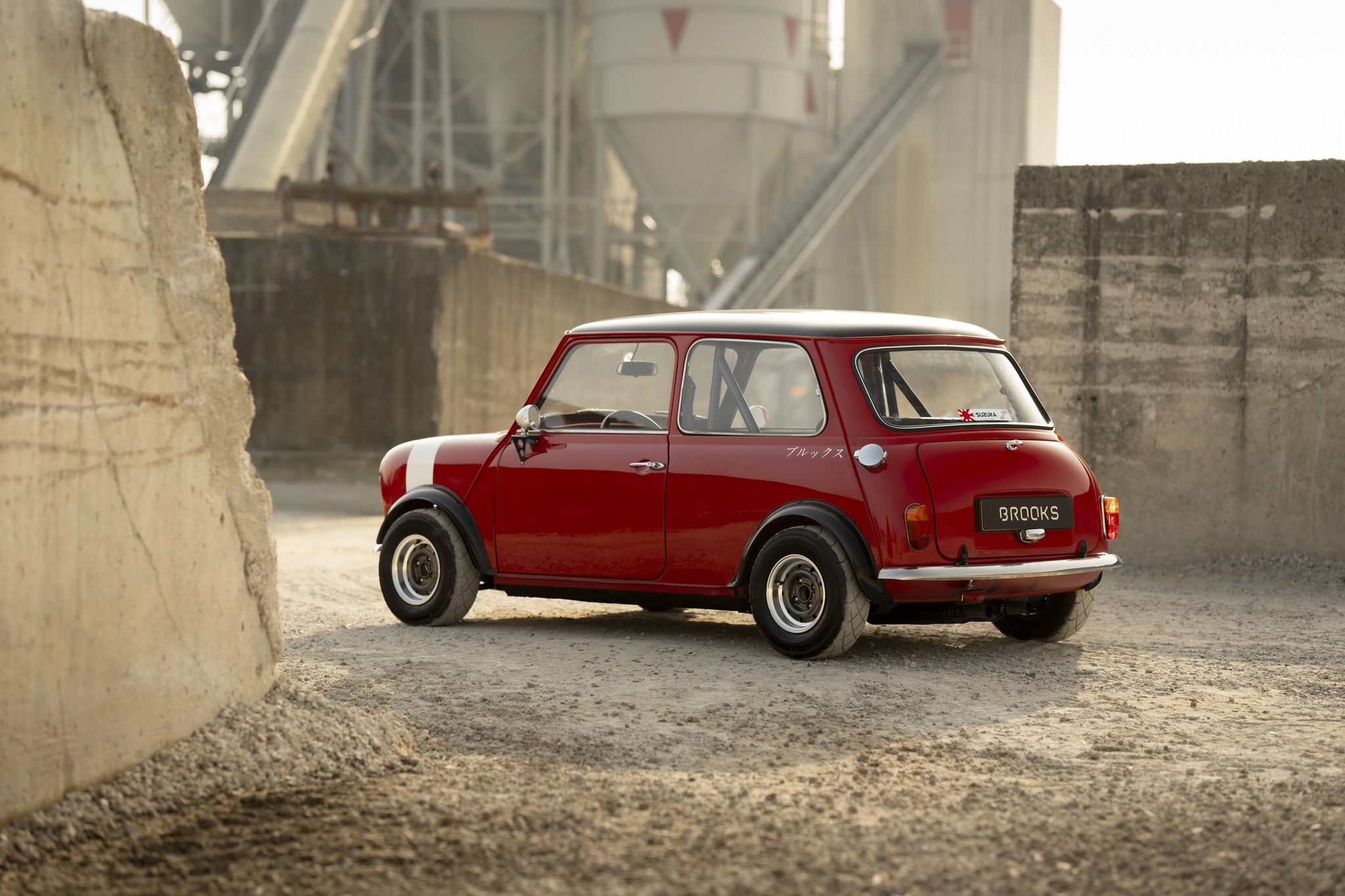Red classic Mini Cooper race car parked on a gravel road.