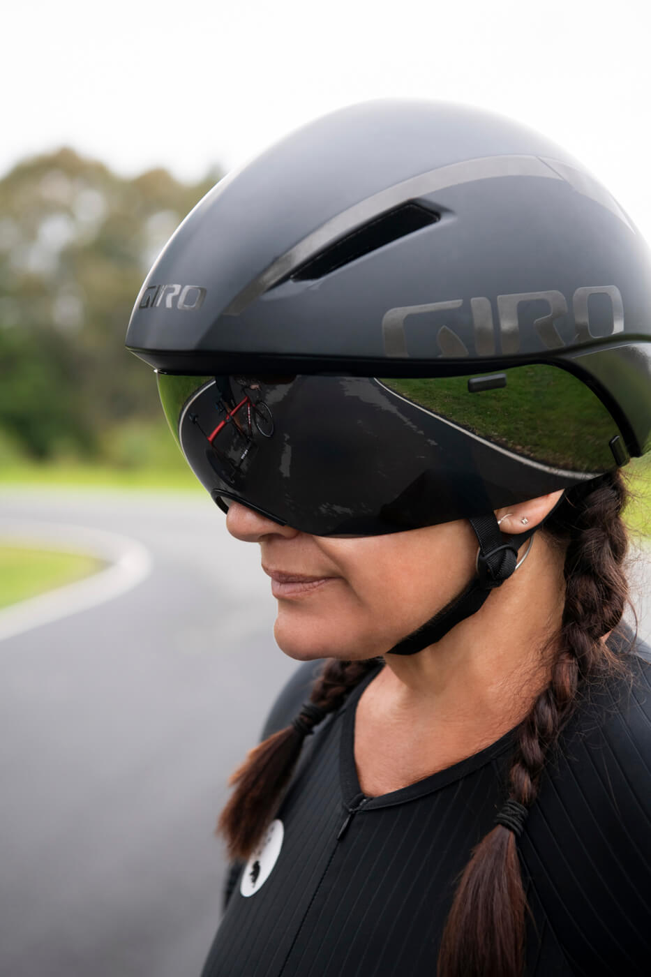 Portrait of Lily on the cycling track in her time trial helmet with the visor down