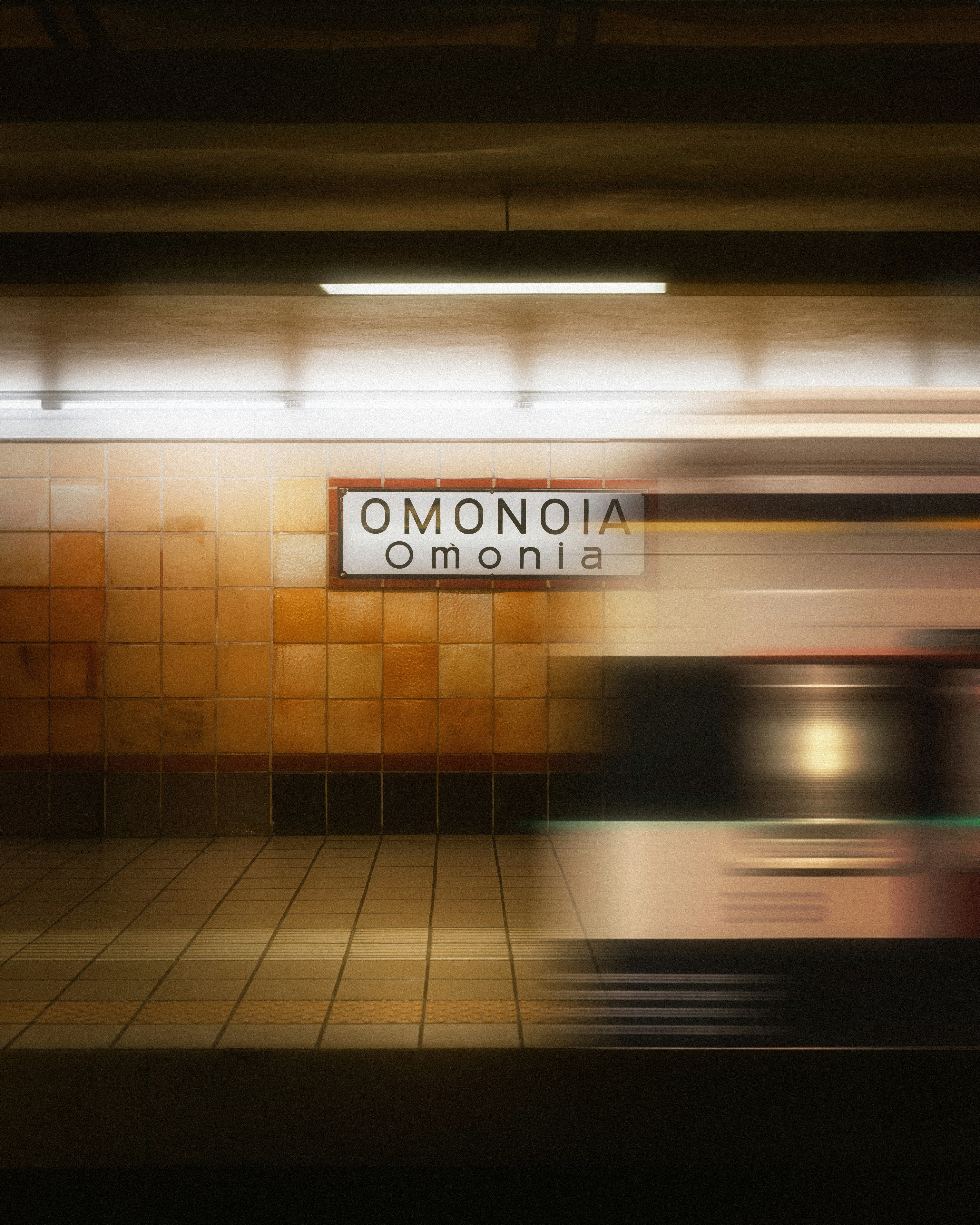 A blurred train passes through omonoia station.