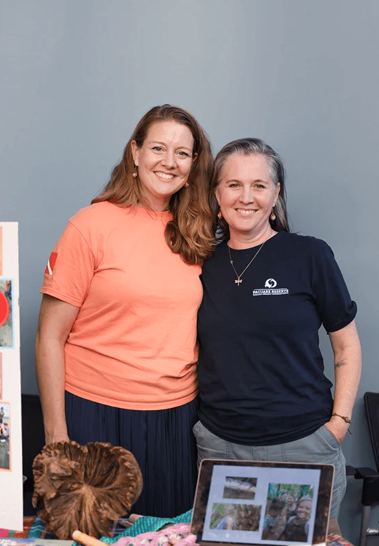 Two teacher fellows smiling together at their end-of-trip showcase, hosted at PEF's office.