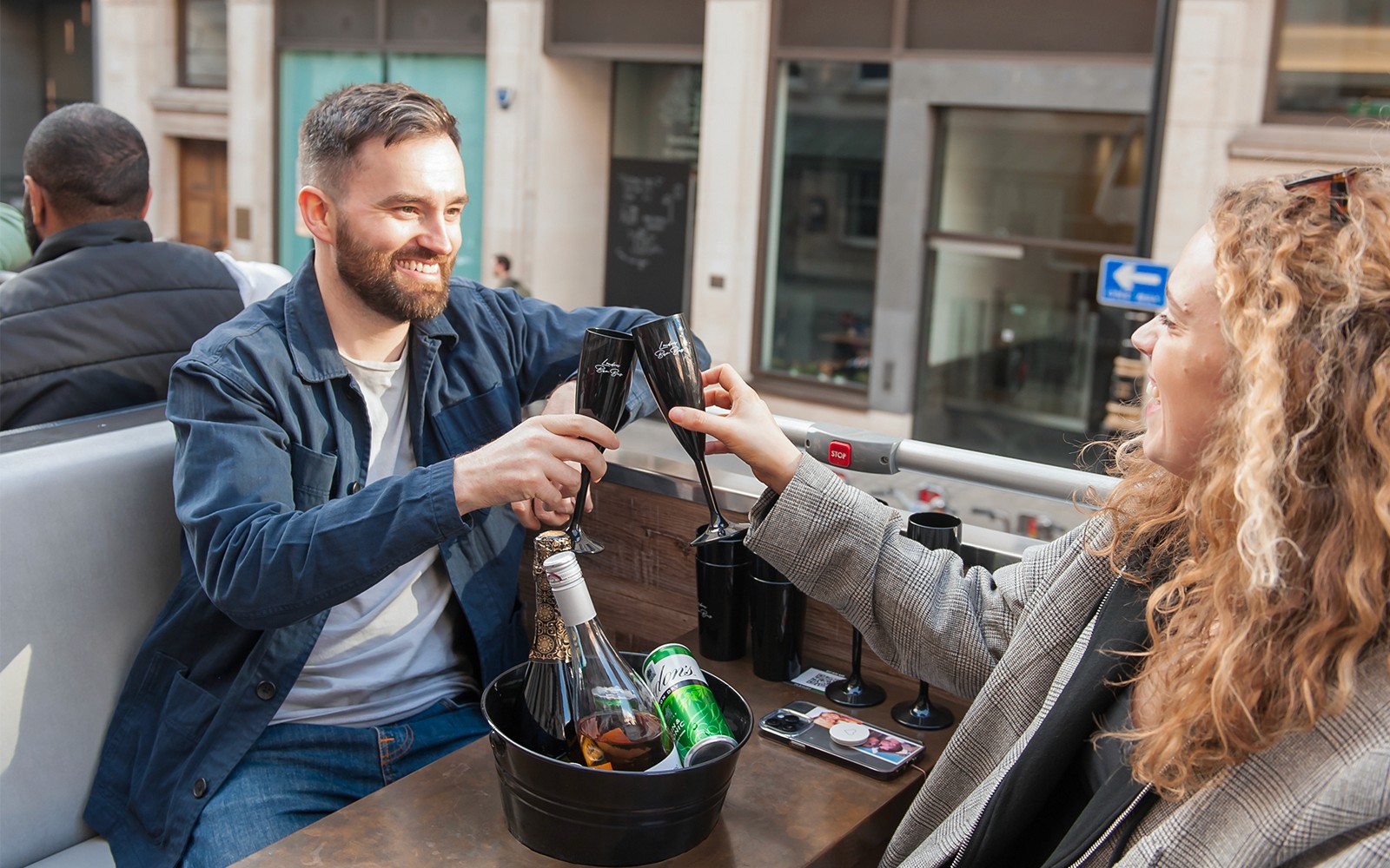 一对男女在敞篷巴士游览中举杯庆祝。