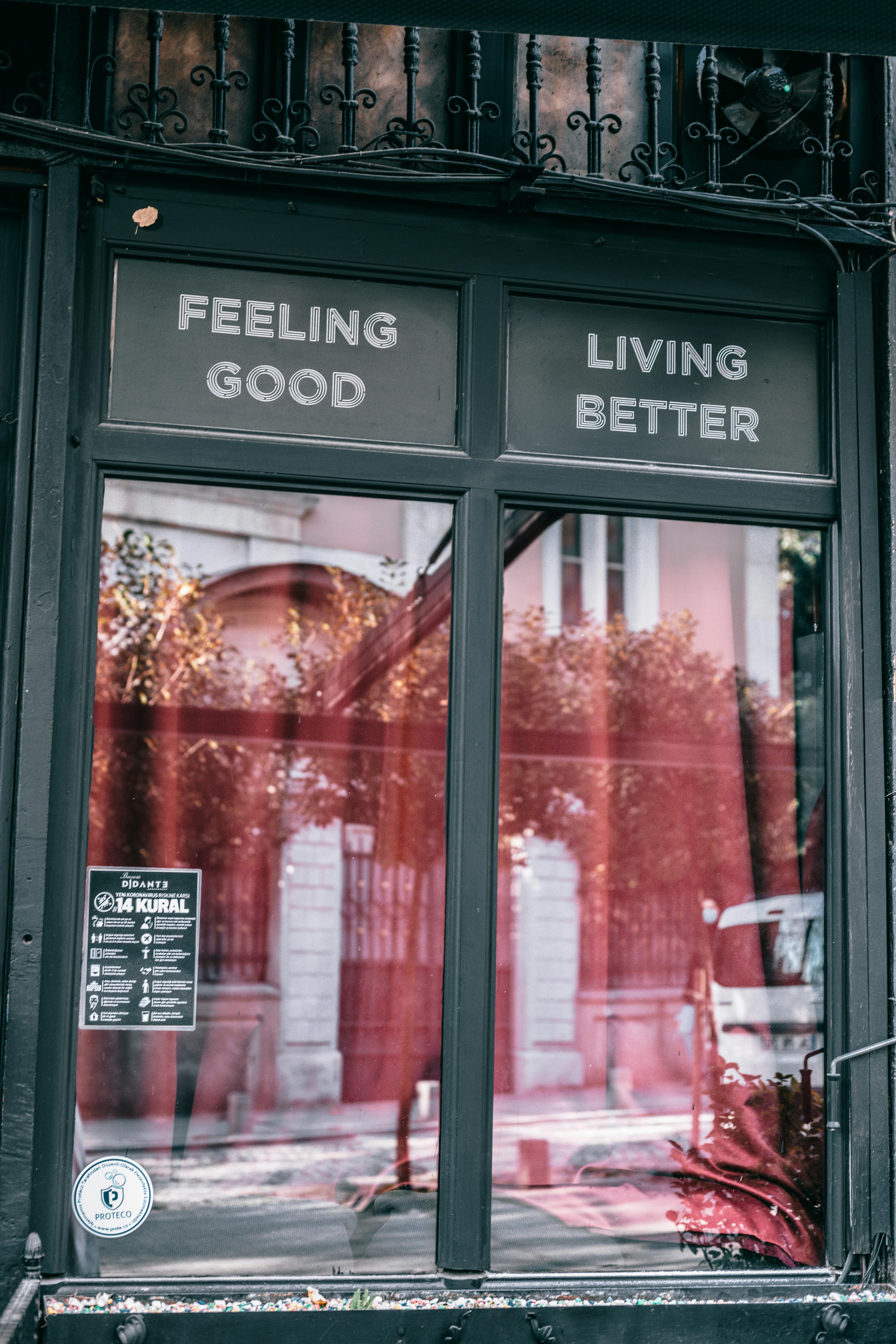 A window with two signs above it saying "Feeling Good" and "Living Better."