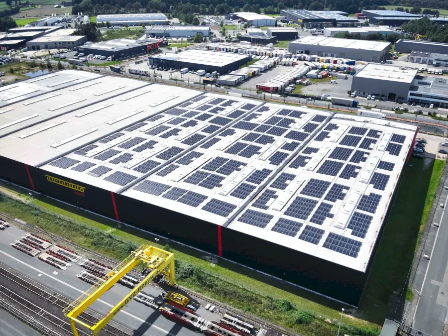 Große Halle mit Solaranlagen auf dem Dach, Logistikzentrum von oben gesehen.