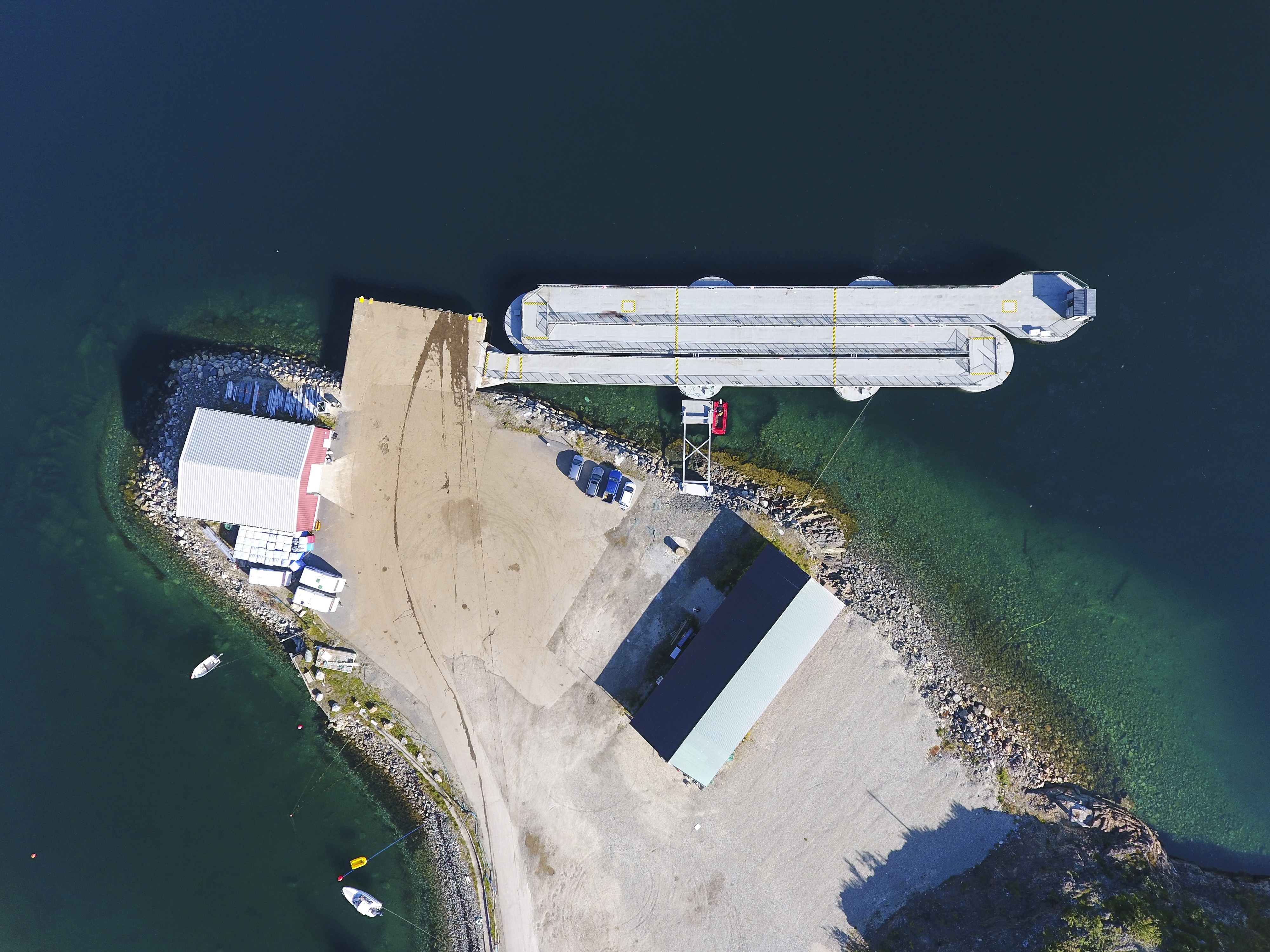 Top-down aerial view of a SeaWalk floating pier system connected to shore, showing access ramp, pontoons and adjacent port facilities along the coastline.