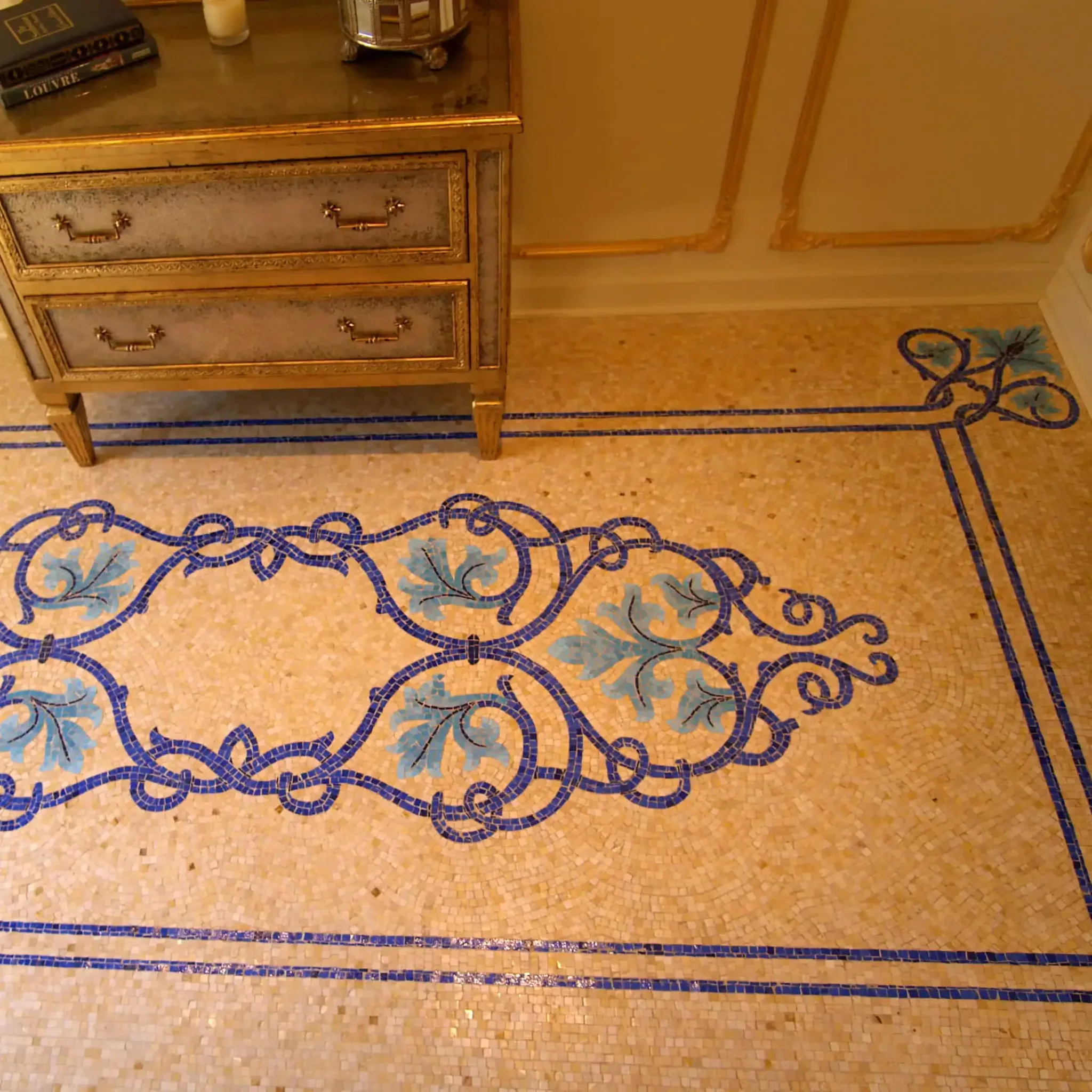Mosaic art design featuring intricate blue and green patterns on a beige tiled floor.