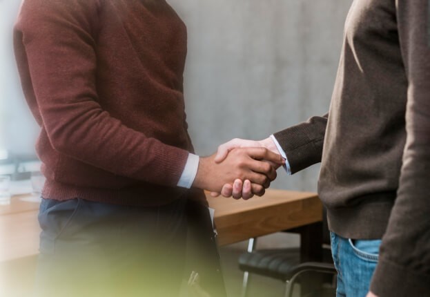 Two professionals shaking hands, symbolizing WooCommerce’s sustained e-commerce partnership support.
