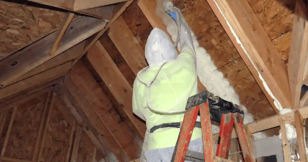 A technician sealing air gaps in an attic with spray foam insulation