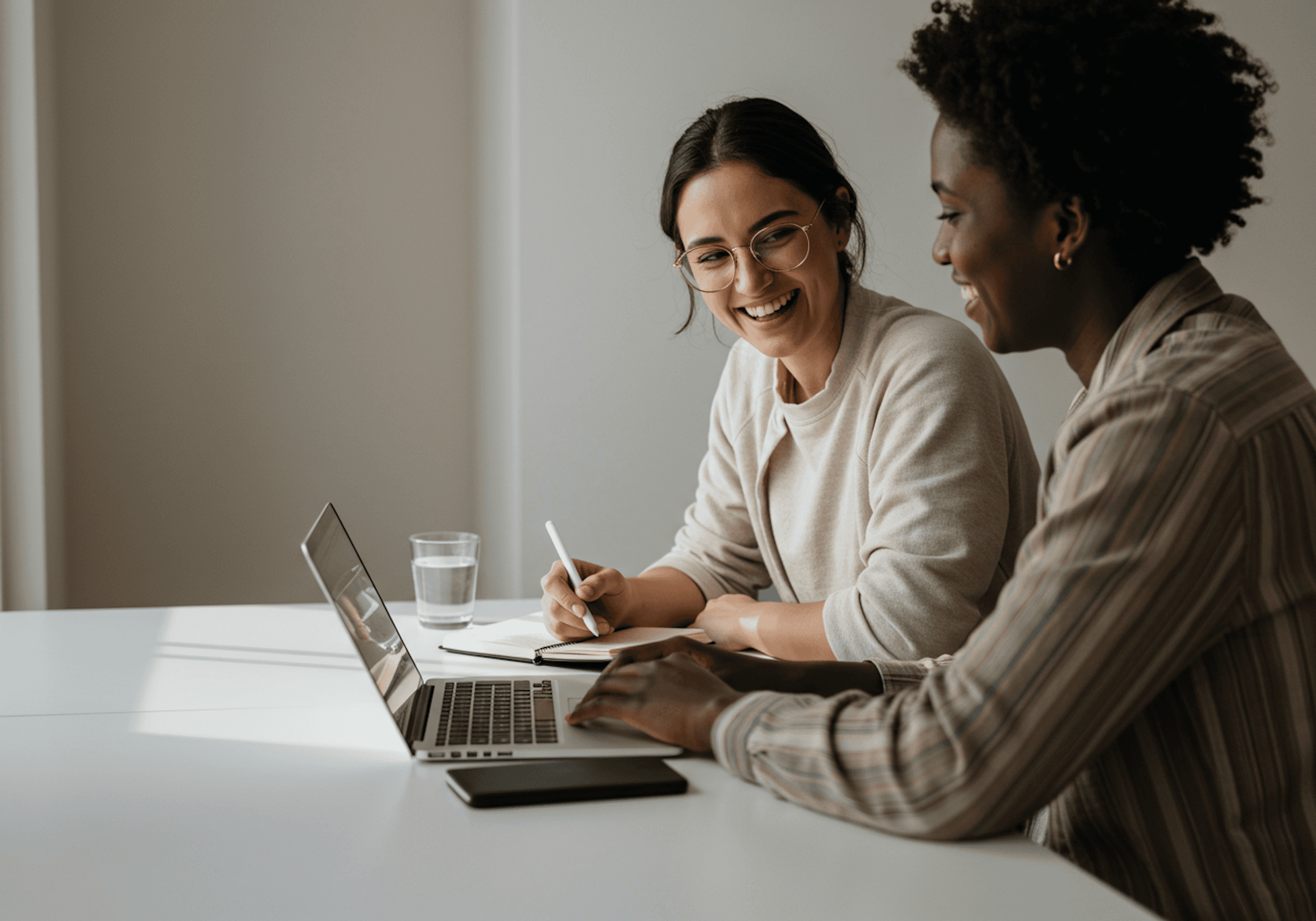 Two people in an office space with the laptop on the desk.