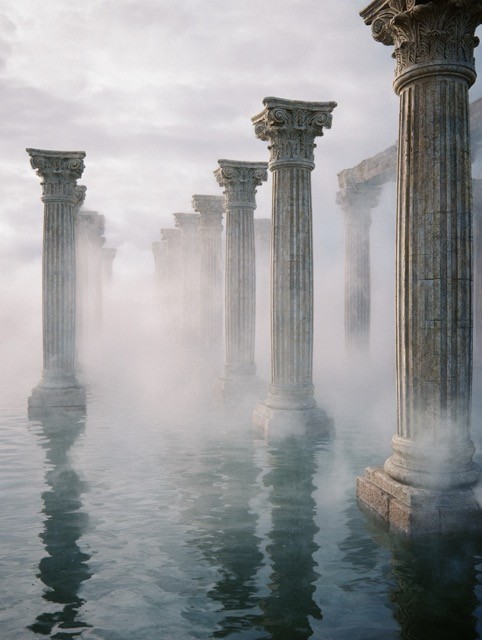 Ancient stone columns rising from misty water, creating a mysterious and atmospheric scene.