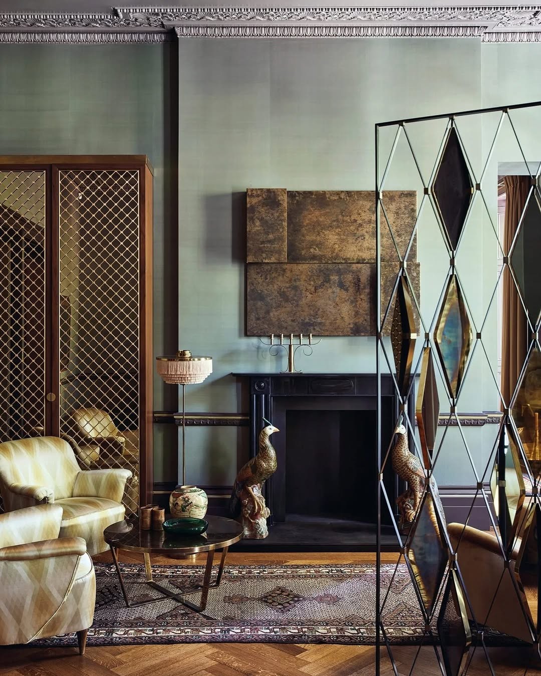 Eclectic living room with a fireplace, mirrored screen, peacock sculptures, and patterned rug.